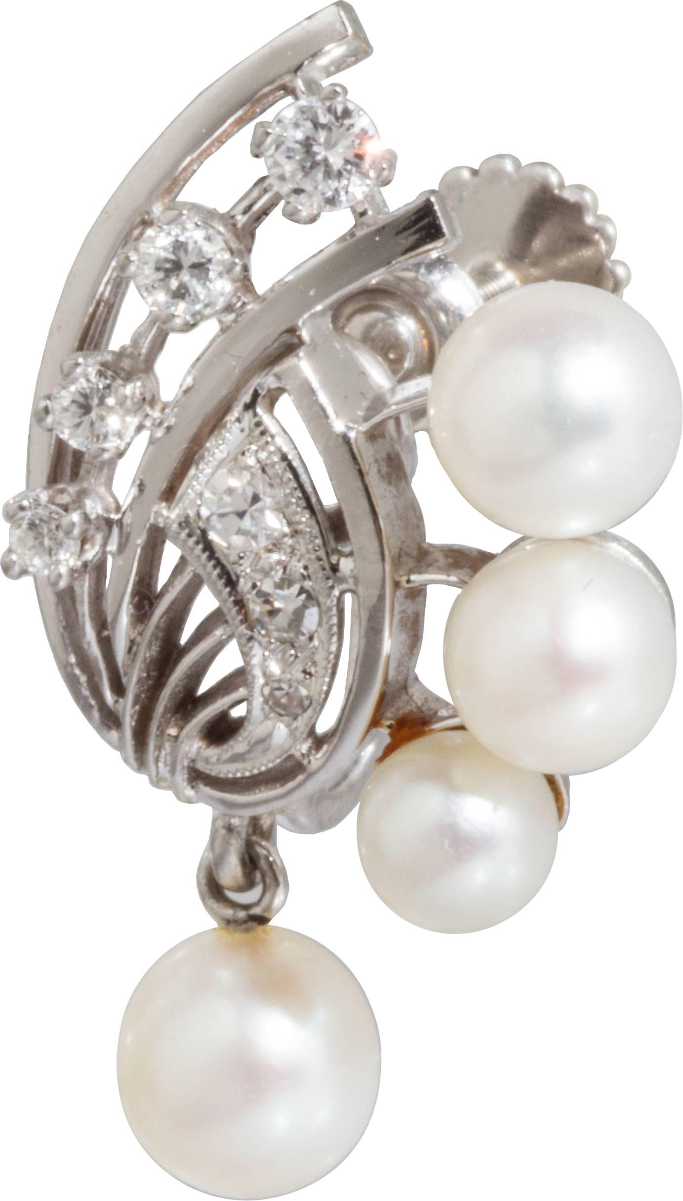 These sophisticated retro earrings incorporate three fixed mounted pearls and one dangling pearl at the bottom that adds movement to them. 
14kt white gold and diamonds complete the design.
They can easily be converted to pierced earrings.