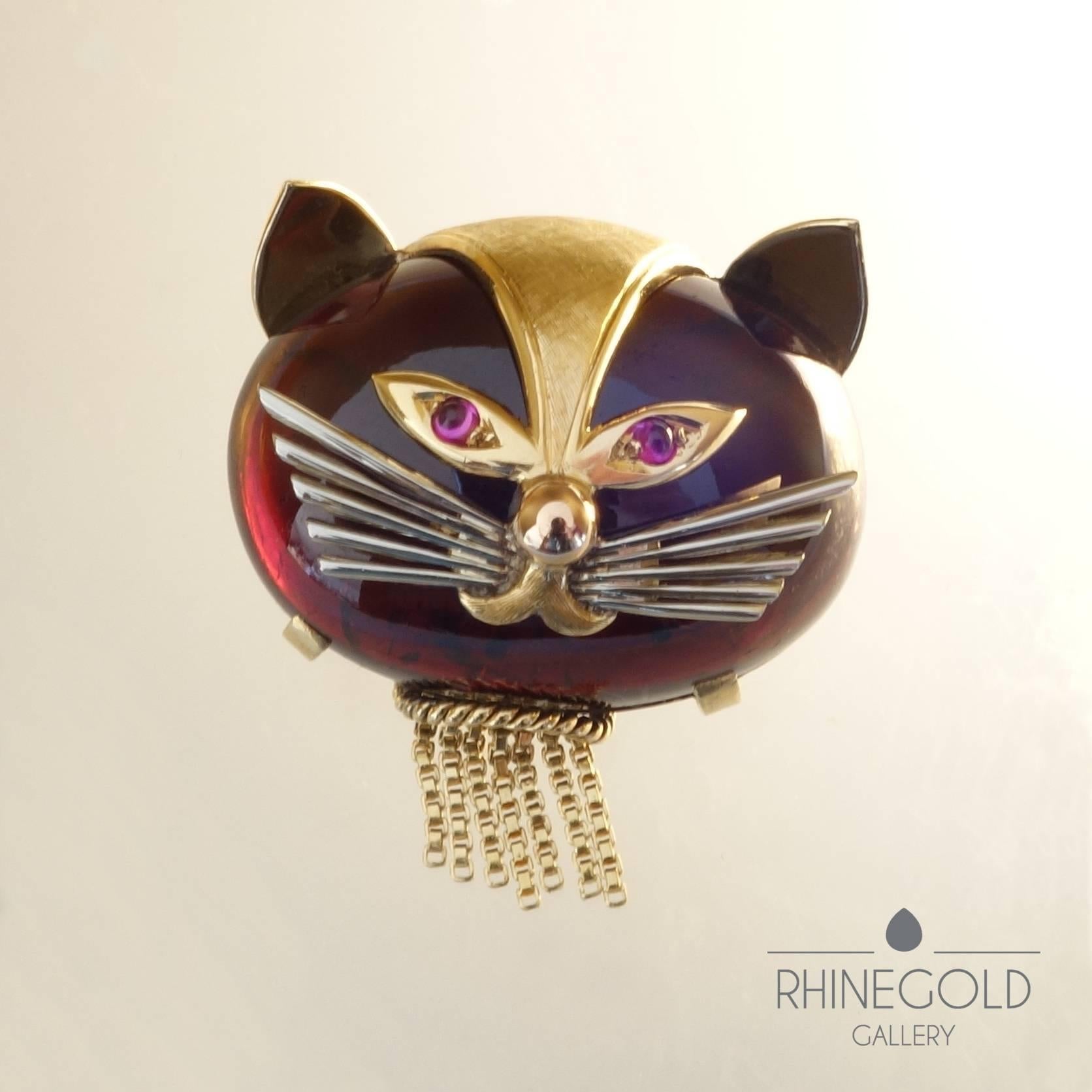 Smart and whimsical – an adorable vintage cat brooch from the 1950/1960s, made of a huge, dark red, almost black garnet cabochon of approx. 80 carats, the features of 18k yellow and white gold, deep pink rhodolite eyes. The fine, flexible gold