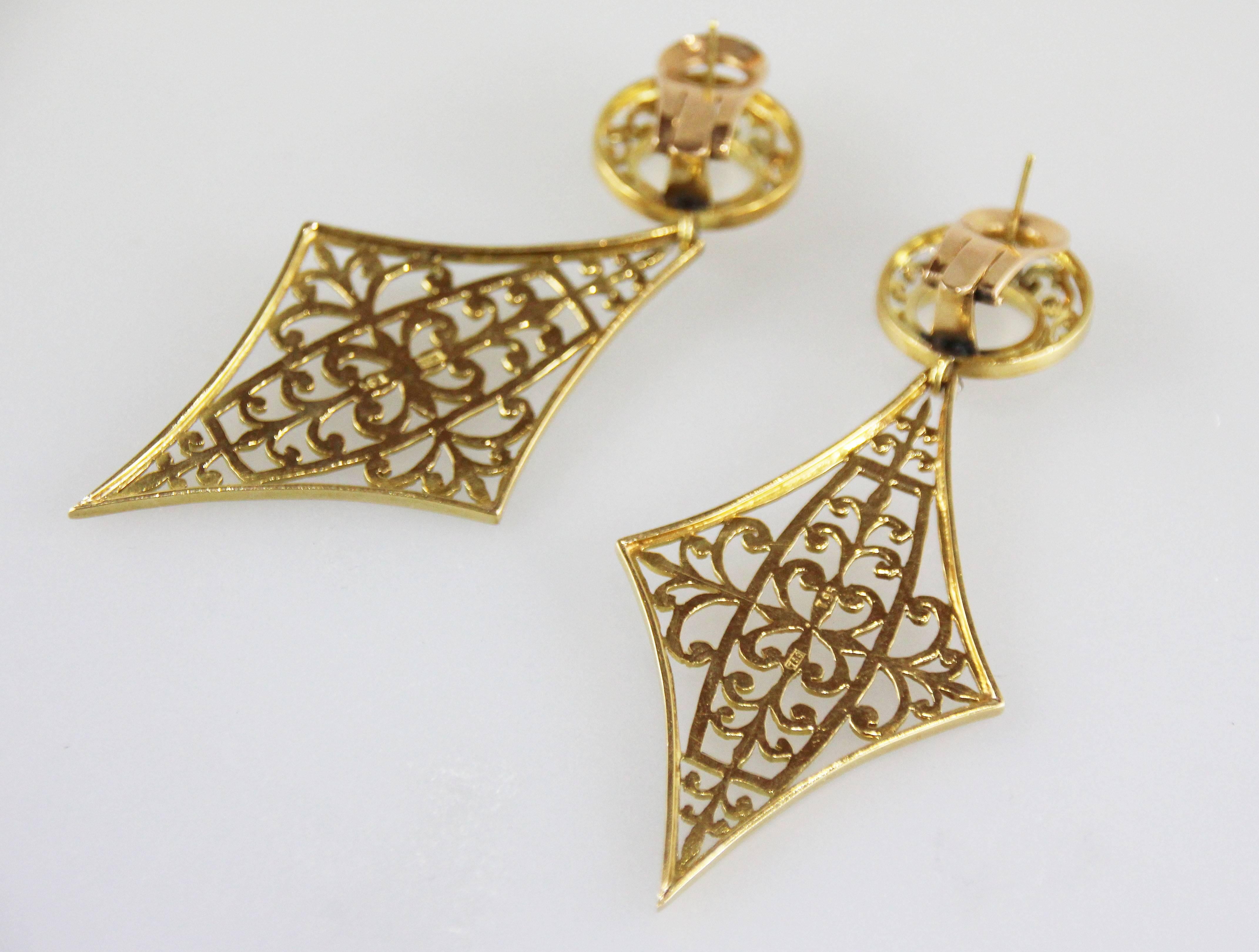 Large earrings with etched details, and a colorless stone connecting the tops and bottoms. 
