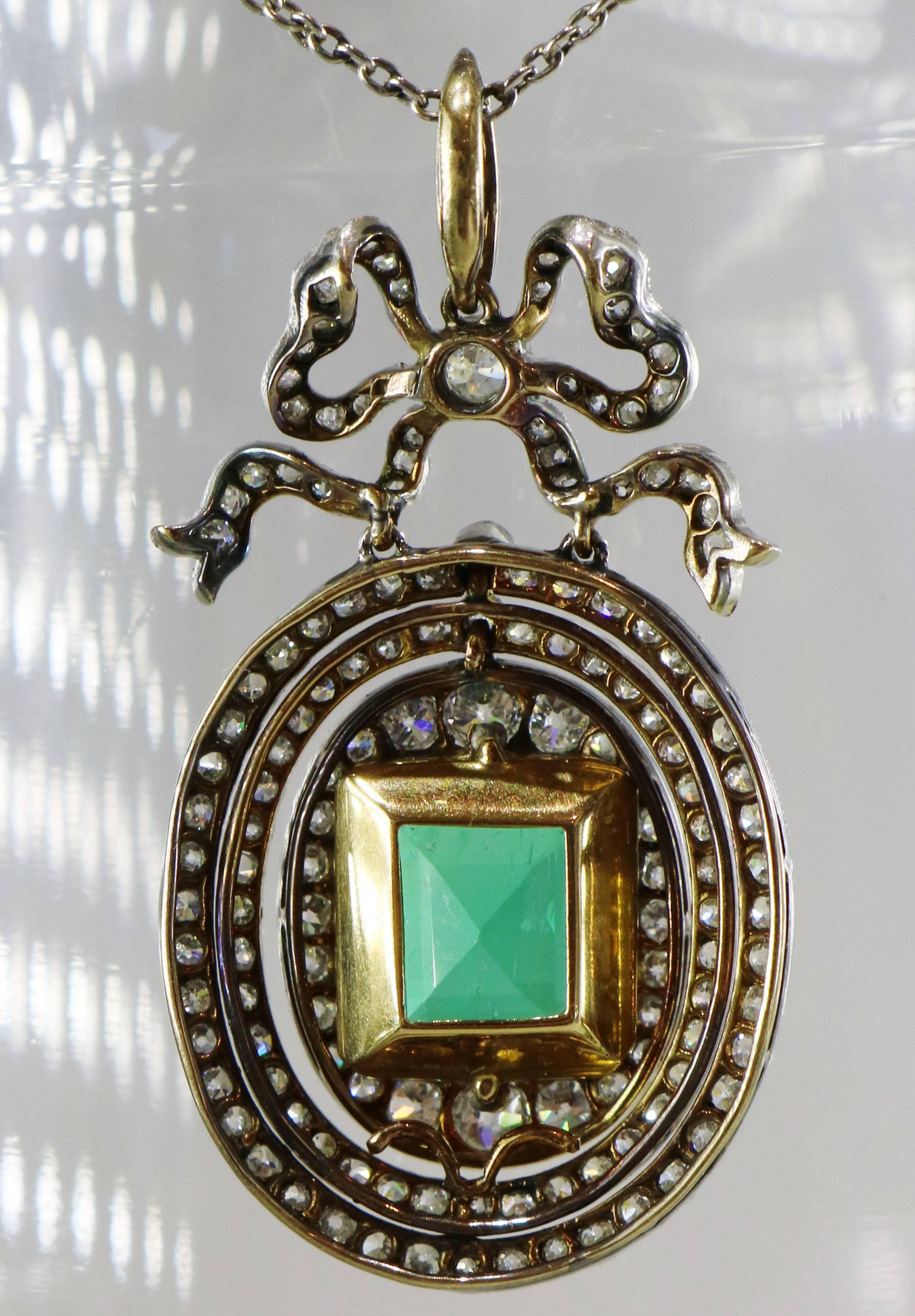 Platinum-topped flexible oval pendant set with over 2.50 carats of old European and single cut diamonds. In the center sits a square cushion cut Colombian emerald weighing over 4 carats. It has an AGL certificate stating that it is Colombian, and