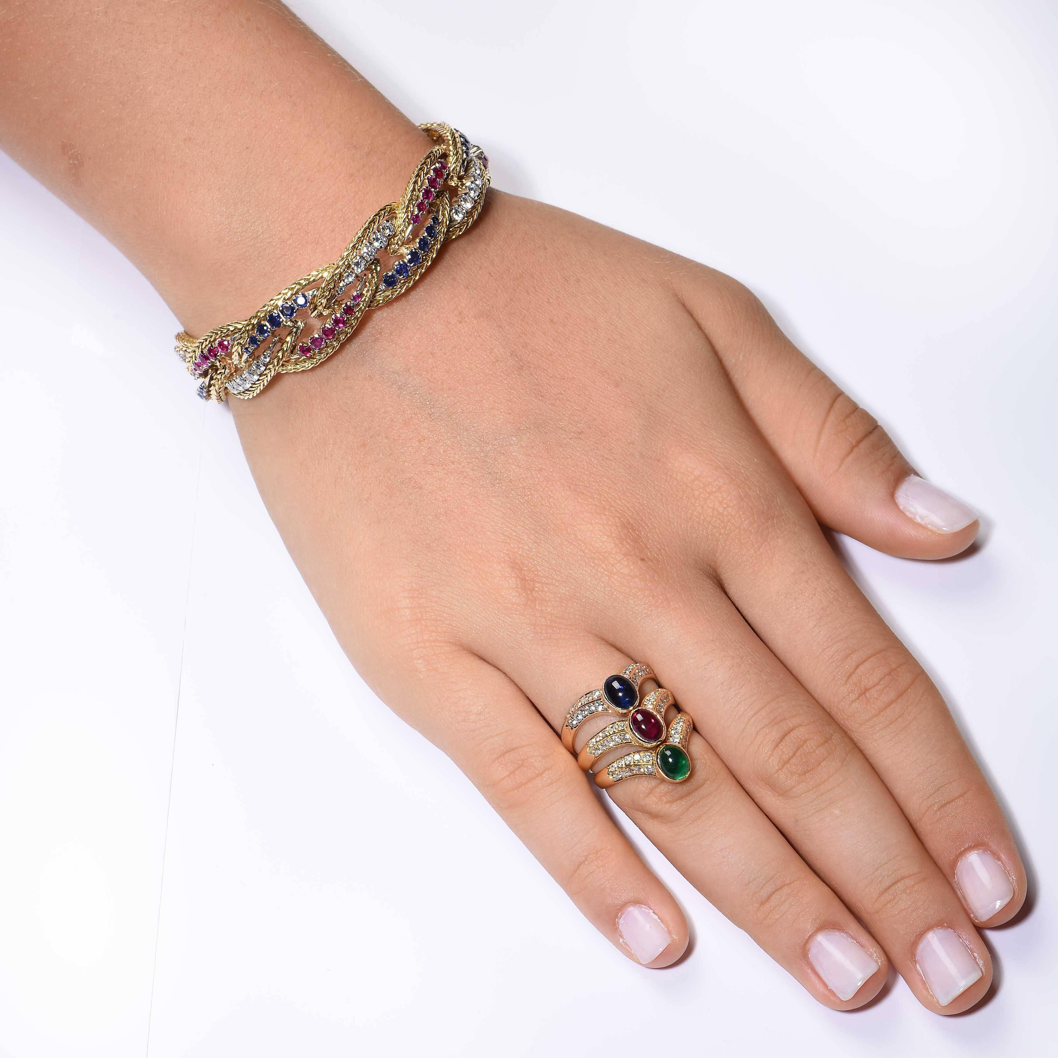 Ce magnifique bracelet tressé des années 1970 est orné de rubis, de saphirs et de diamants. Les diamants ronds de taille brillant pèsent environ 2 carats. Il est également orné de rubis et de saphirs. 

Longueur : 6 3/4 pouces
Type de métal : or