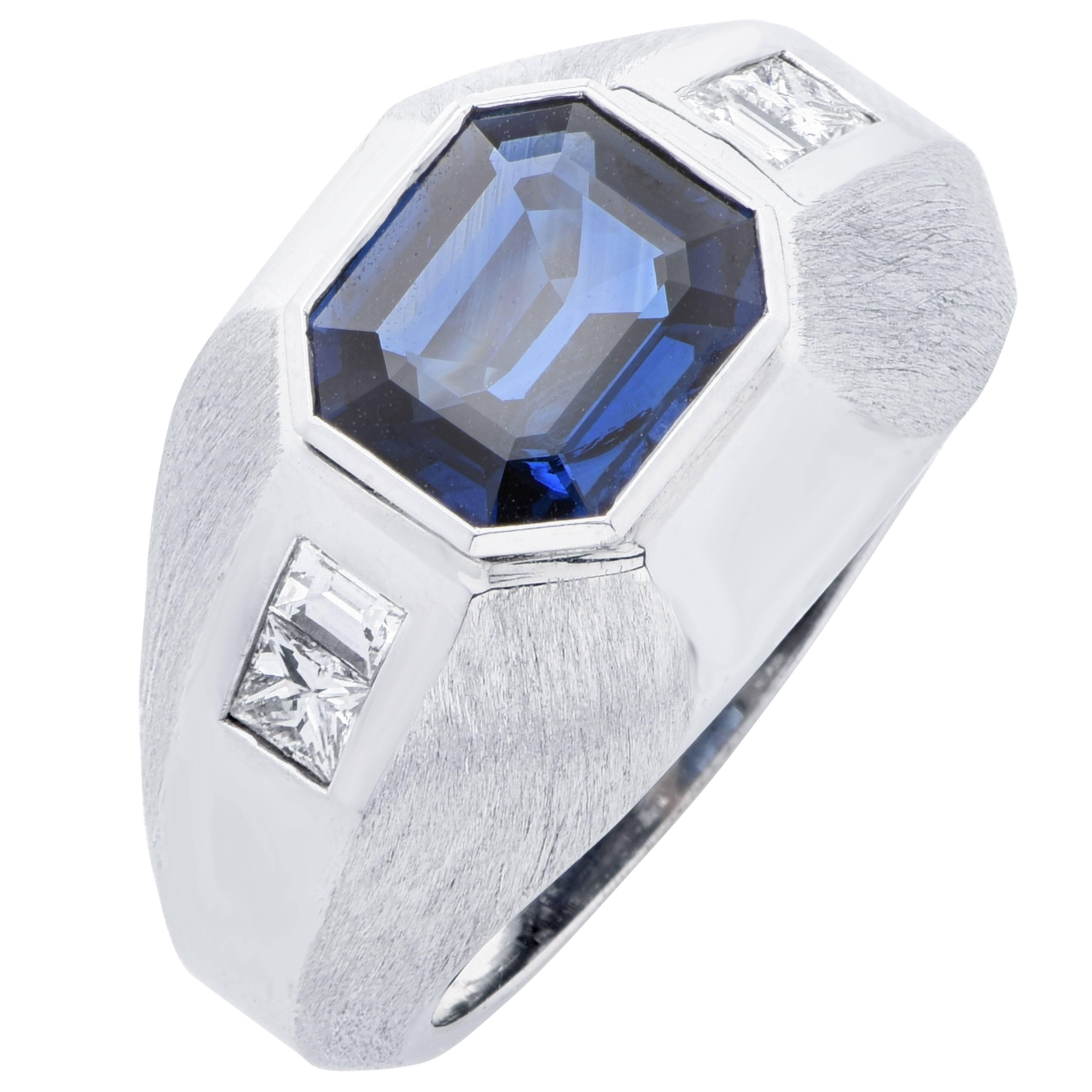 This men's ring features an emerald cut Sapphire weighing 3 carats and 4 mix cut diamonds which weigh 0.85 carats. This ring alternates in high polish and matte finish.  

Ring Size: 9 1/2 (Can be sized)
Metal: 18 Kt White Gold (stamped and/or