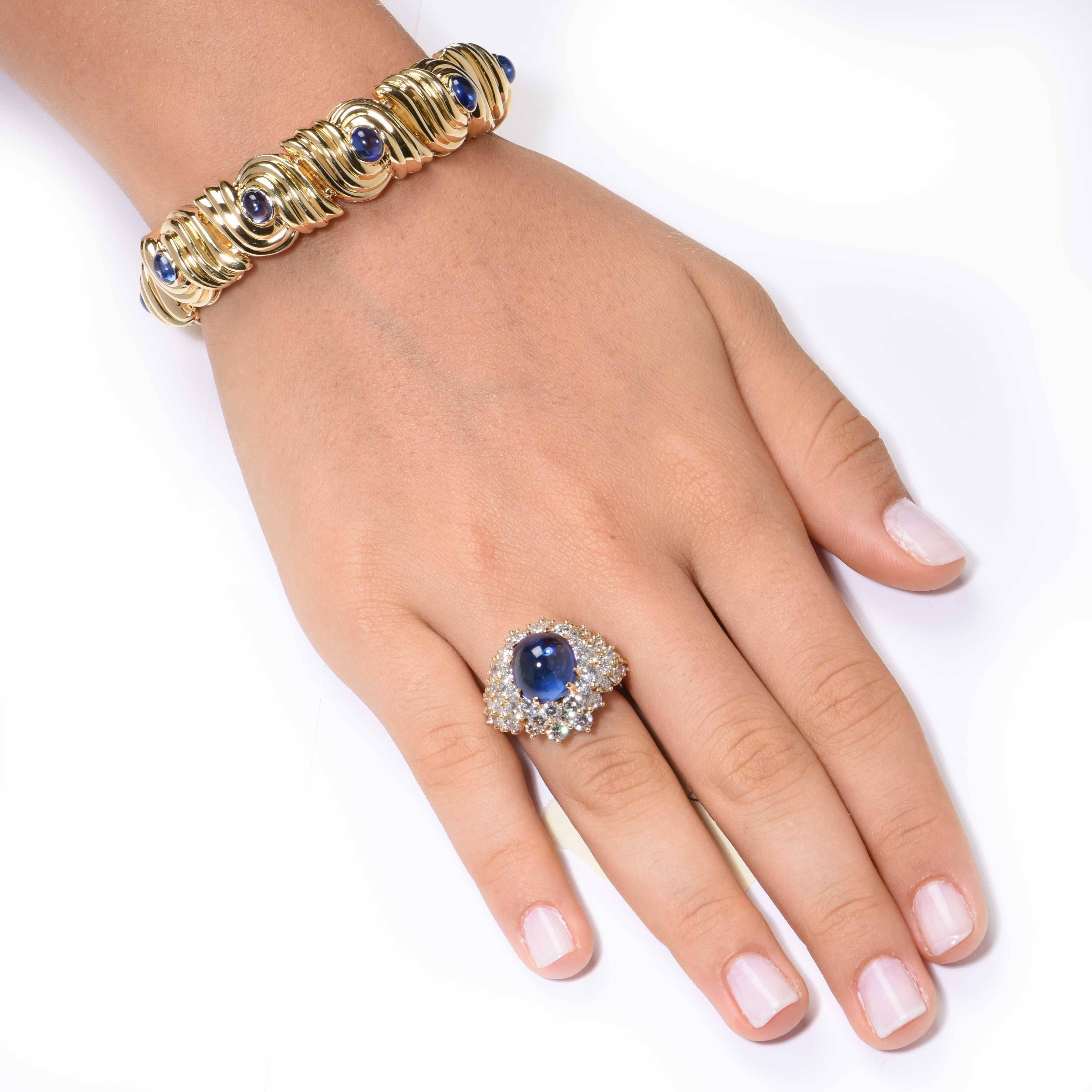 This beautiful and vibrant Kurt Wayne ring features a cabochon Sapphire weighing approximately 9.80 carats, and 52 round brilliant cut diamonds weighing approximately 5.70 carats. Diamonds are F/G in color and VS in clarity. 

Ring size 6 1/2 Can be