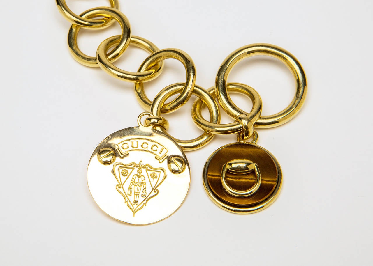 Bold open links graduating in size and finished with a toggle clasp are enhanced with two stylish pendants, one with tiger's eye. Classic Gucci style and quality. 22 1/2 inches in length.