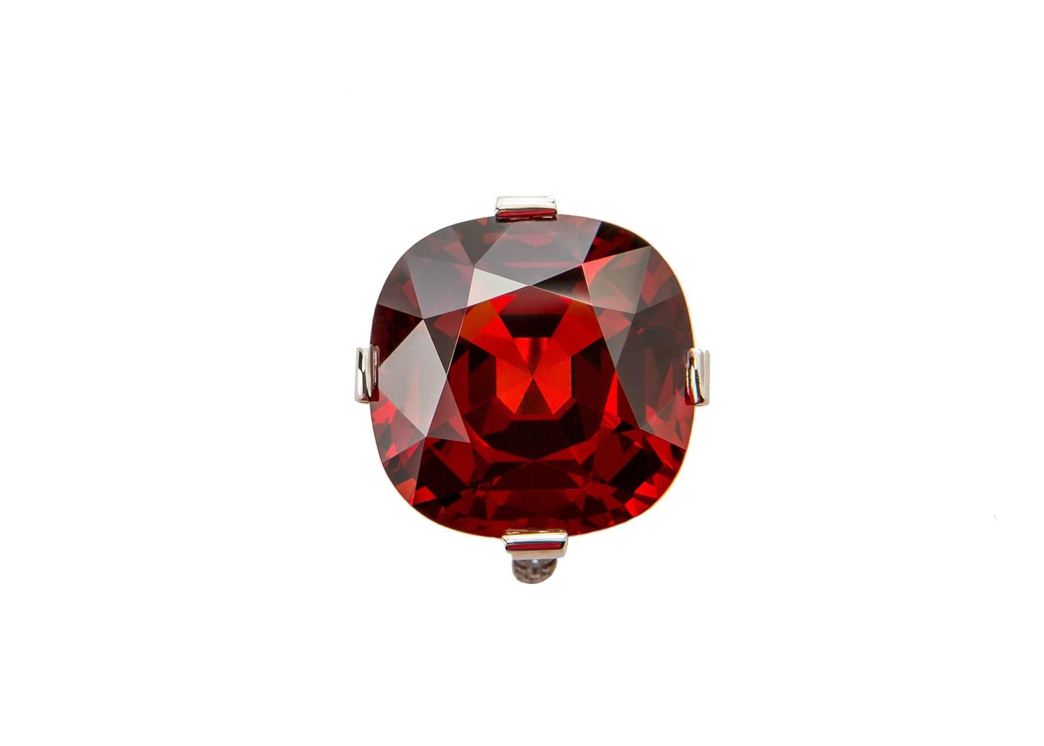 This is rare and exceptional 22.59 carat cushion cut spessartite garnet. The brilliant color is a rich mixture of red, brown and orange. A handmade platinum mounting finished with brilliant cut diamonds was created to elegantly showcases this