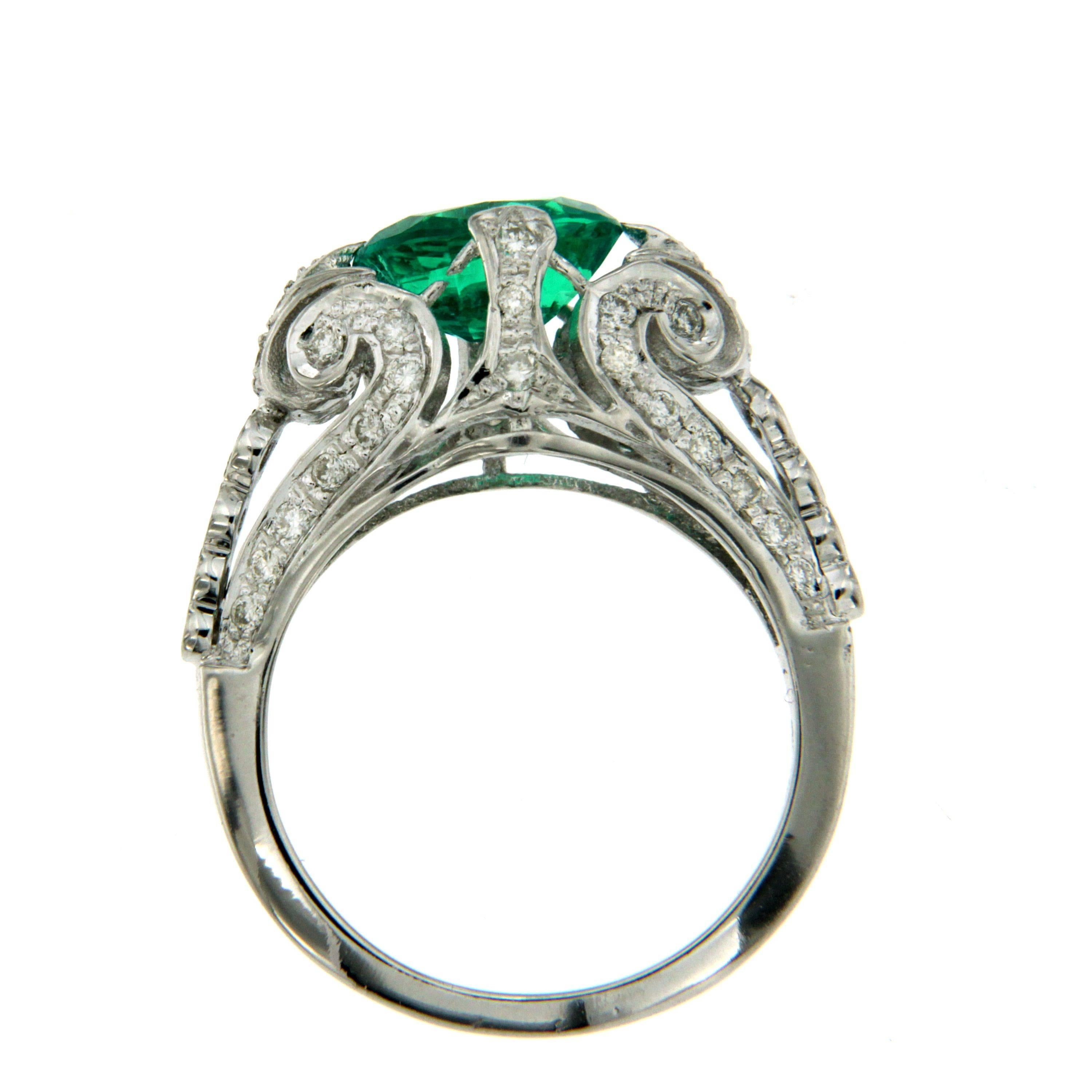 A beautiful Engagement ring, set with an oval mixed cut synthetic Vivid Emerald of absolute beauty weighing an 1.55 ct, surrounded by old mine-cut diamonds, weighing approx. total of 1.00, with diamond set shoulders, mounted in 18k white gold. 