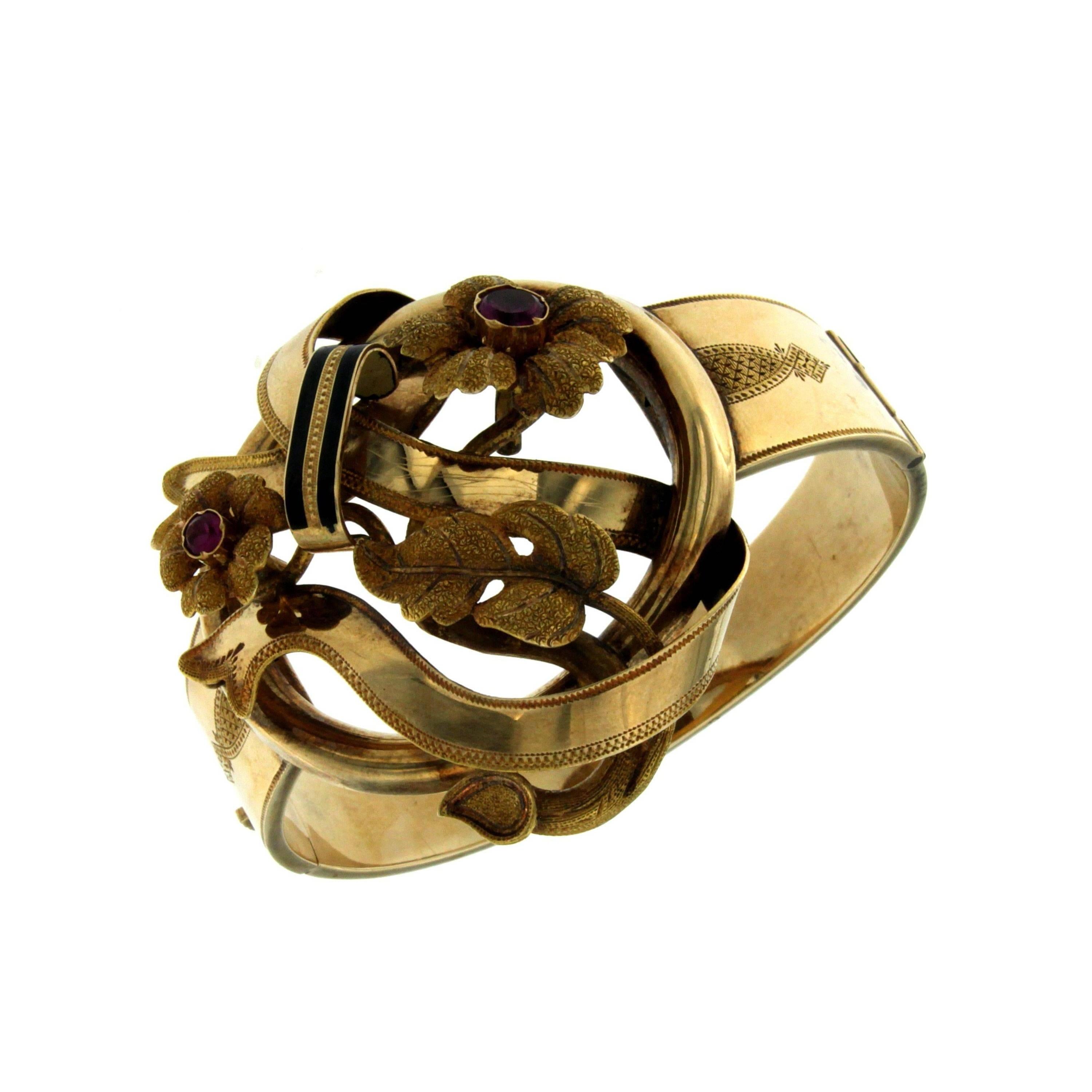 This gorgeous bangle bracelet with neoclassical engraved top is crafted in 14K yellow gold and weighs approx. 35.4 grams. It features beautiful shapes of flowers and leaves adorned by two purple glass stones.
Secure catch. 
Diameter: 6.50 cm