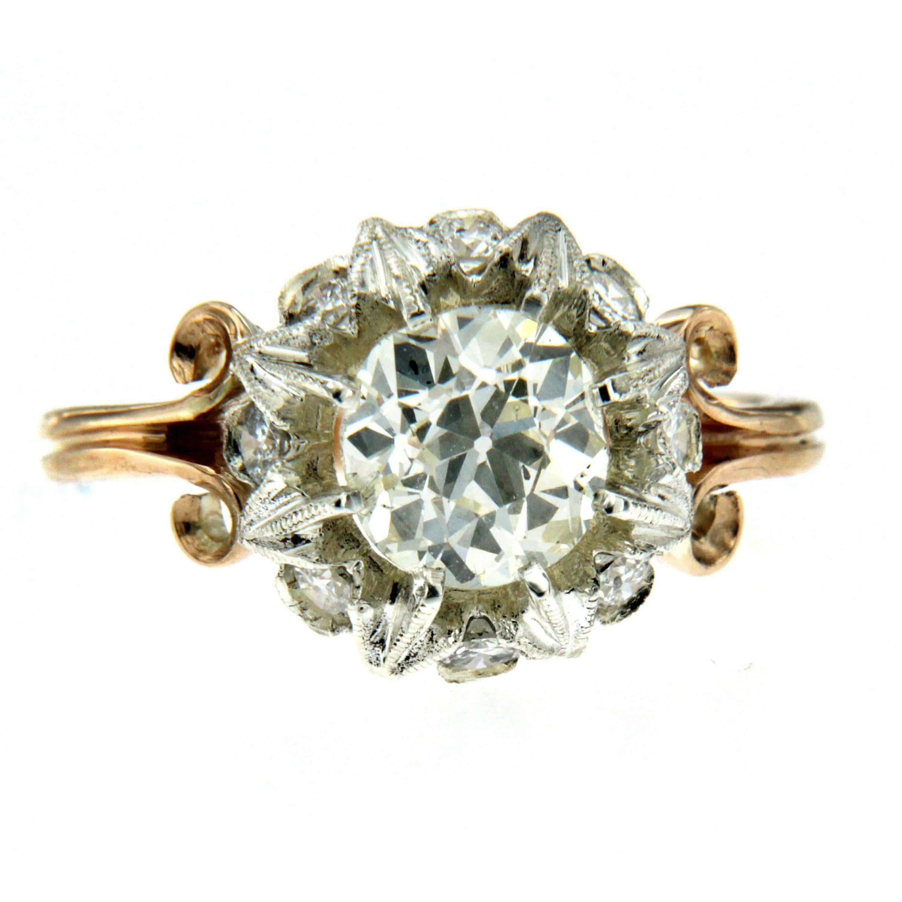 A beautiful original and unique Art Noveau diamond engagement ring set in 18K yellow and white gold hand worked into a gorgeous blooming flower. The ring features a center 1.40 carat old mine cut diamond M color Vvs, 
Framing the center diamond are