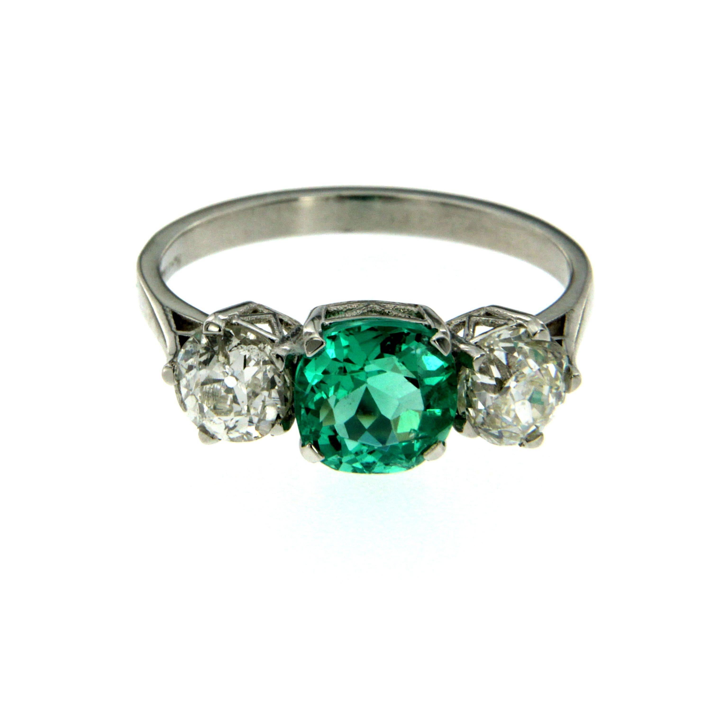 Classic three stone Platinum ring with a mixed cut Emerald weighing approximately 1.33 carats and 2 old american cut diamonds with a total weight of approximately 1.38 carats. The Emerald is free of any treatment as oil or resin.

CONDITION: