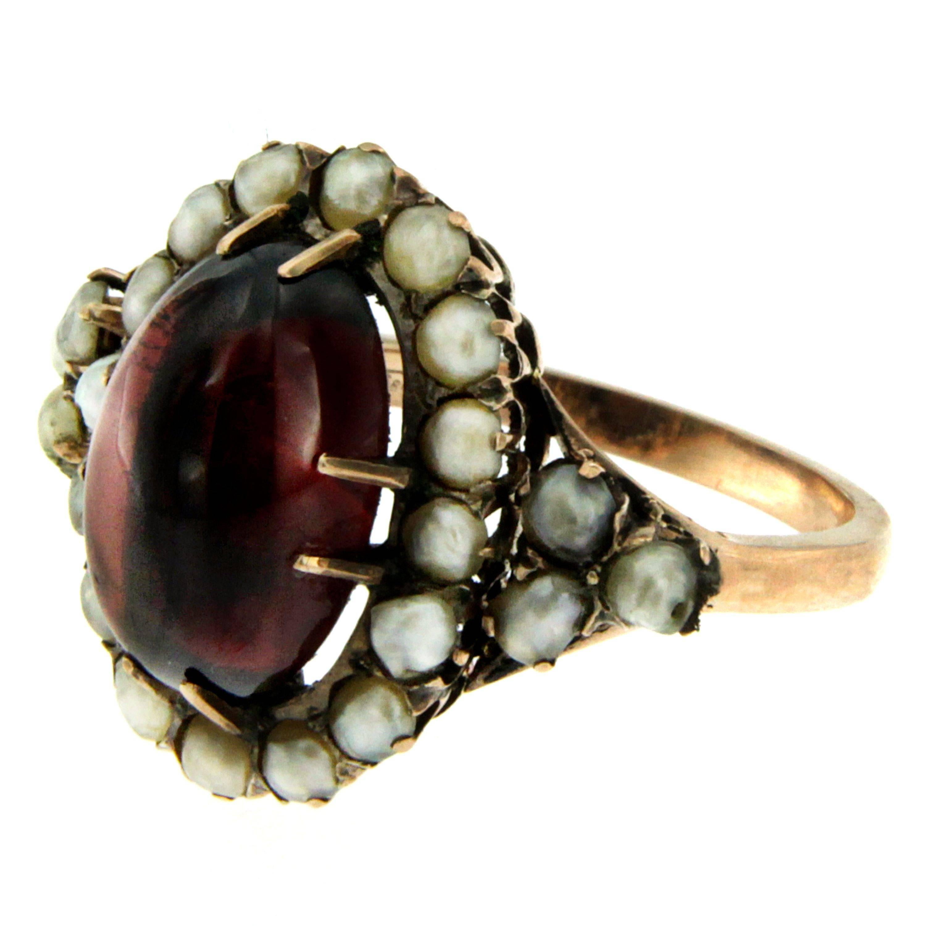 Victorian Garnet Bashra Pearl Halo Ring. The Garnet measures 15.29mm x 11.27mm  and is flanked by small bashra natural pearls.
Hand crafted in 12k rose gold. Circa 1890

CONDITION: Pre-owned - Excellent 
METAL: 18k rose Gold
GEM STONE: Garnet,