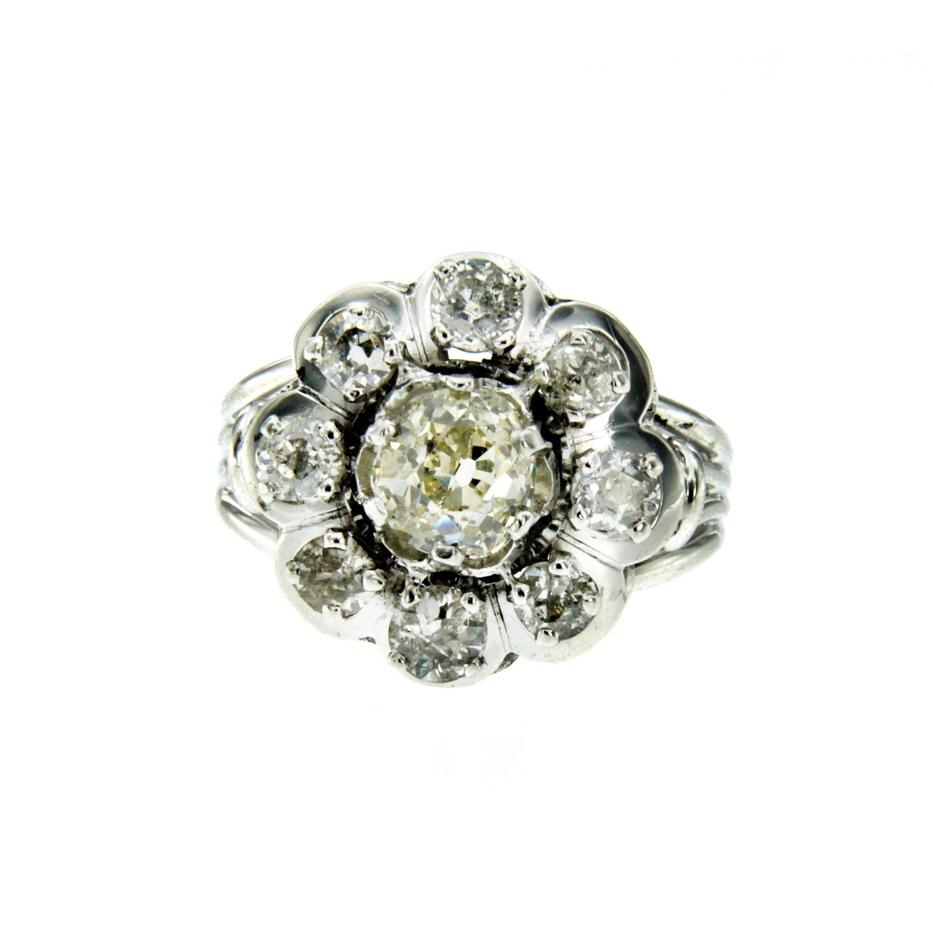 A 18k white Gold Art Deco ring featuring a flower design set in the center with a 1.30 ct old mine-cut diamond L color VS clarity, surrounded by 8 old mine-cut diamonds weighing 1.60ct. graded H/I color vs clarity. Circa 1930 

CONDITION: Pre-owned