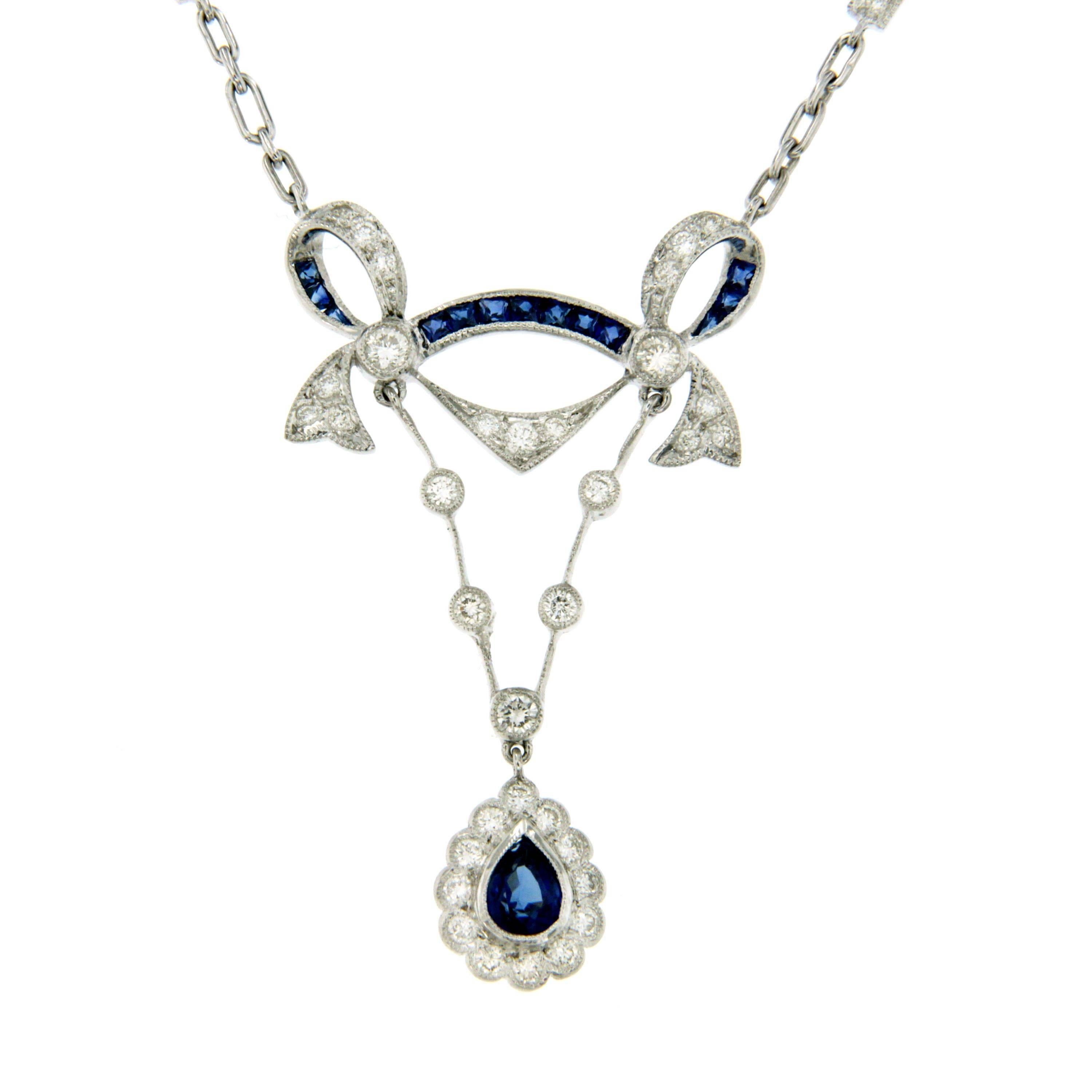 Cluster pendant, featuring a pear-shaped sapphire framed by round brilliant cut diamonds suspended on a gold chain adorned by diamonds and sapphires. 
Sapphires weighing approximately 1 ct and diamonds weighing approximately 0.60 total
