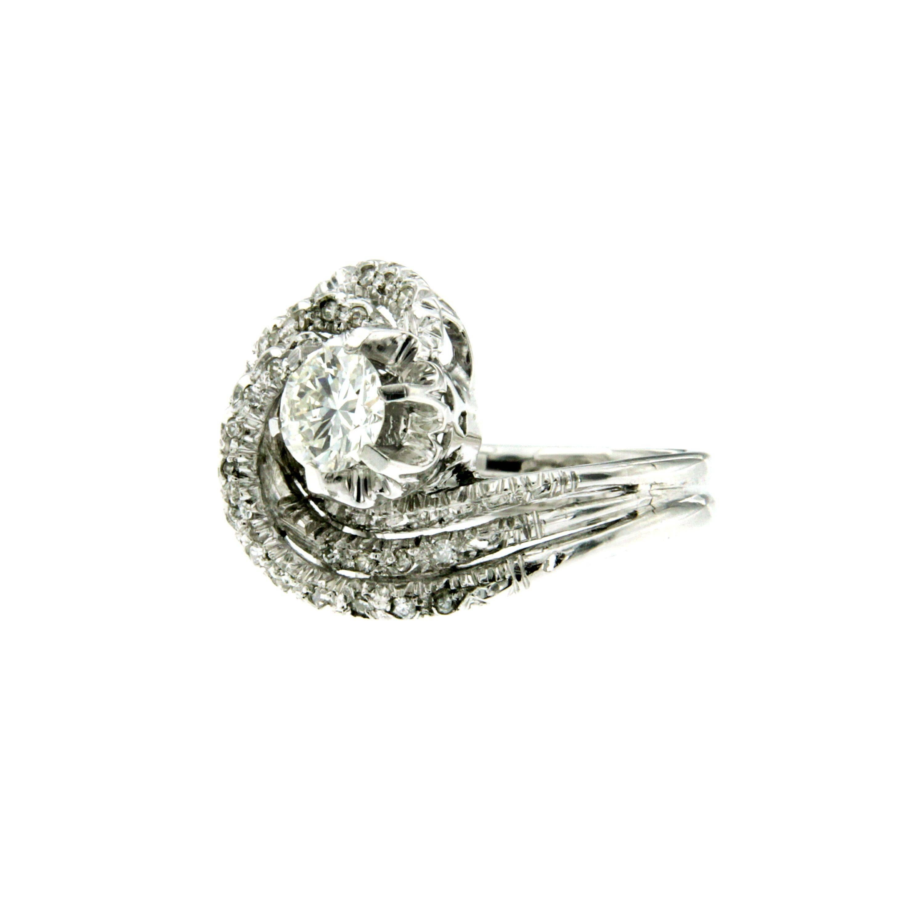 Unusual and elegant vintage diamond ring features a round brilliant cut diamond weighing 0.60 carats H color VVS, surrounded by smaller diamonds totaling approximately 0.15 carat. Circa 1970

CONDITION: Pre-owned - Excellent 
METAL: 18k white Gold