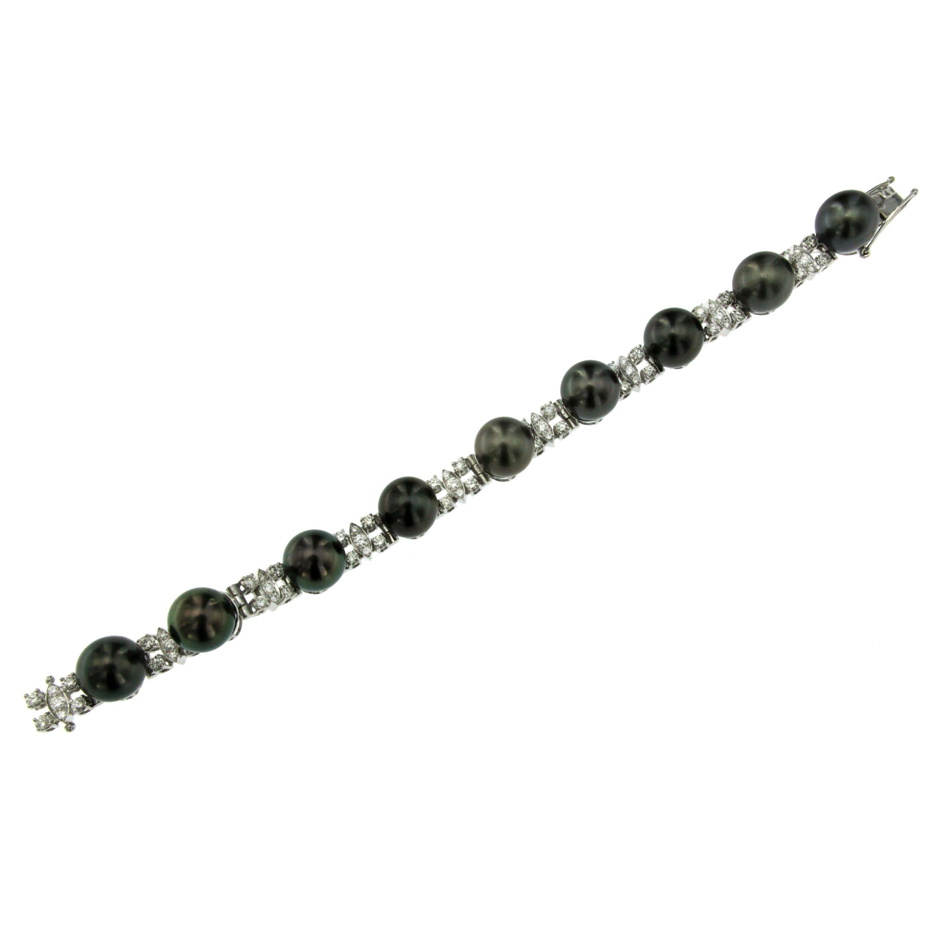 Ce magnifique bracelet est serti de diamants ronds incolores taille brillant d'environ 2,70 carats, alternant avec des perles de Tahiti noires de 11 mm.  Attrayante et merveilleusement réalisée en or blanc 18 carats. Circa 1980

ÉTAT : Usagé -