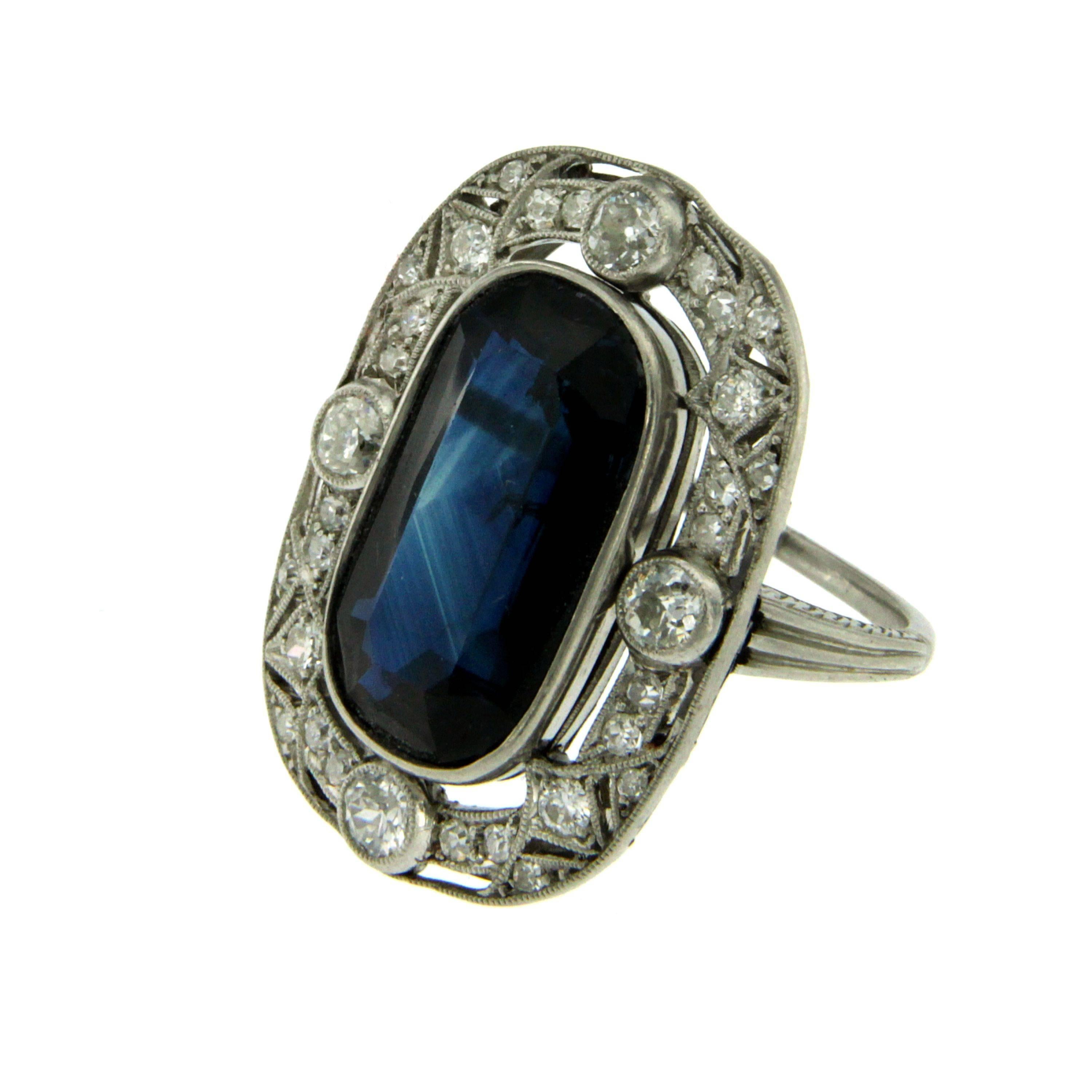 Authentic and rare Art Deco engagement ring centered with a large 10 cts natural Sapphire, surrounded by old mine cut diamonds, weighing cumulatively 1.70 cts, graded G-H color and VS. The shank of the ring is engraved with a beautiful vintage