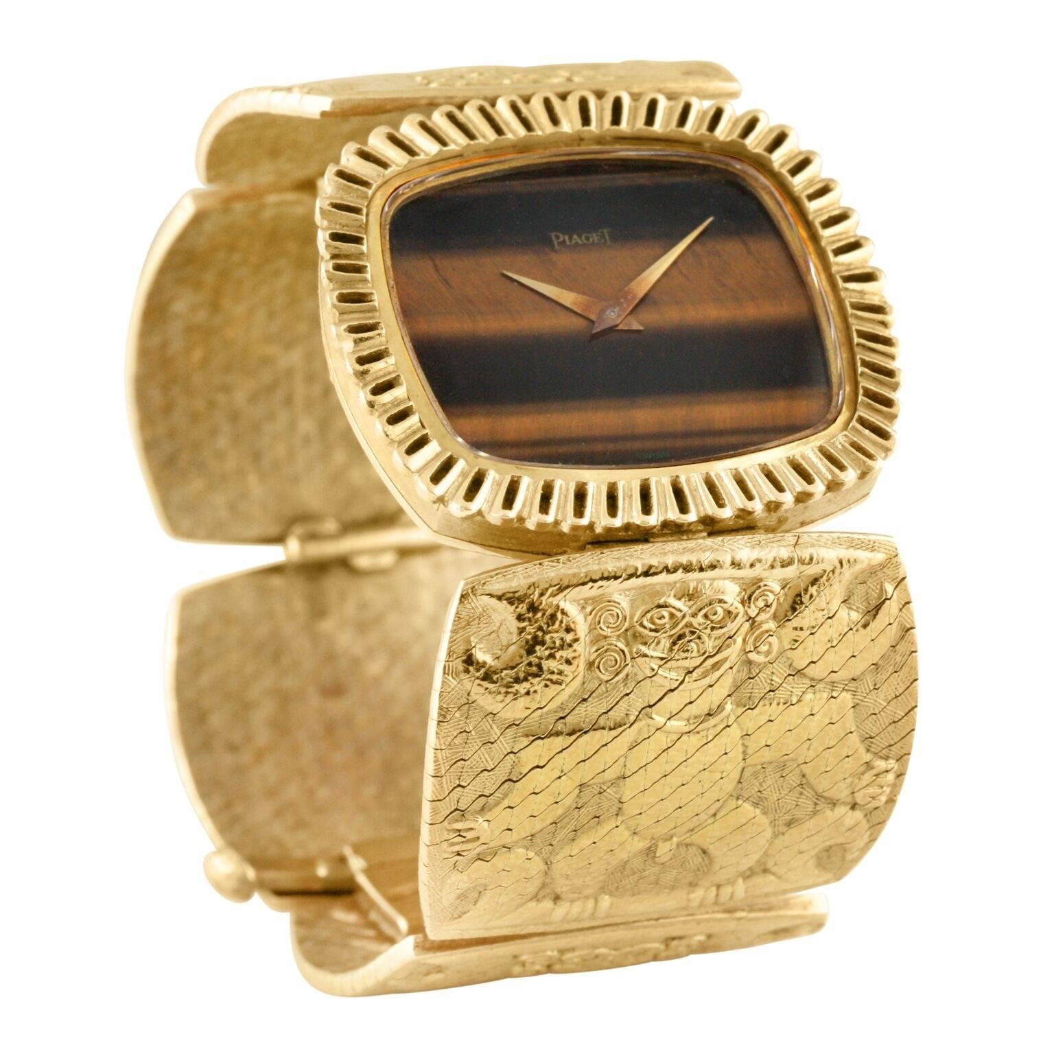 Manufactured in the early 1970's, this highly unusual and rare Piaget bracelet watch is truly one-of-a-kind. Bracelet is sculptural with relief images of 'Inca' figures in 18k solid yellow gold. Unique decorated bezel with a fitted Tiger's Eye stone