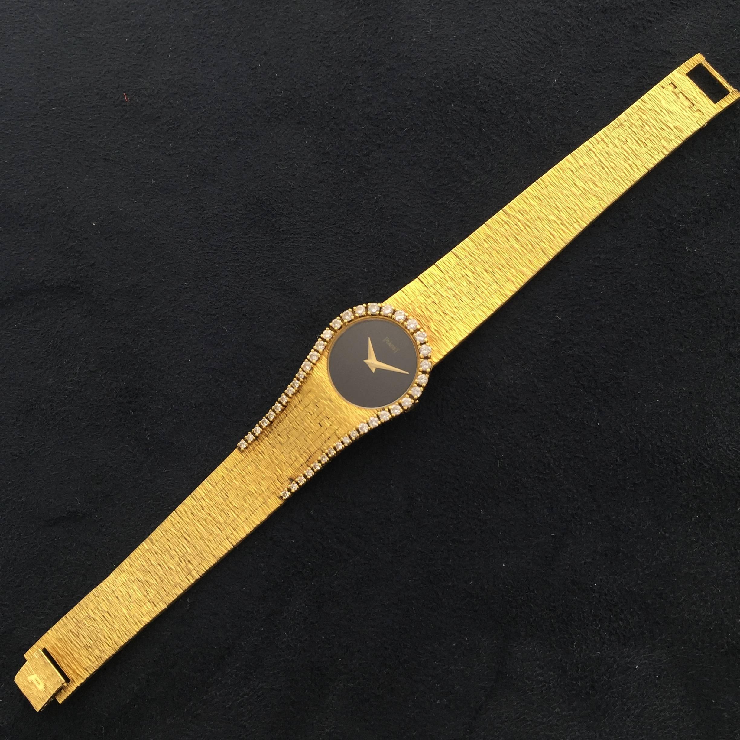 Circa 1970, this 18kyellow gold Piaget bracelet watch with bonyx dial and diamond horseshoe design. Textured geometric hand-finished bracelet. An elegant and rare lady's jewelry watch.