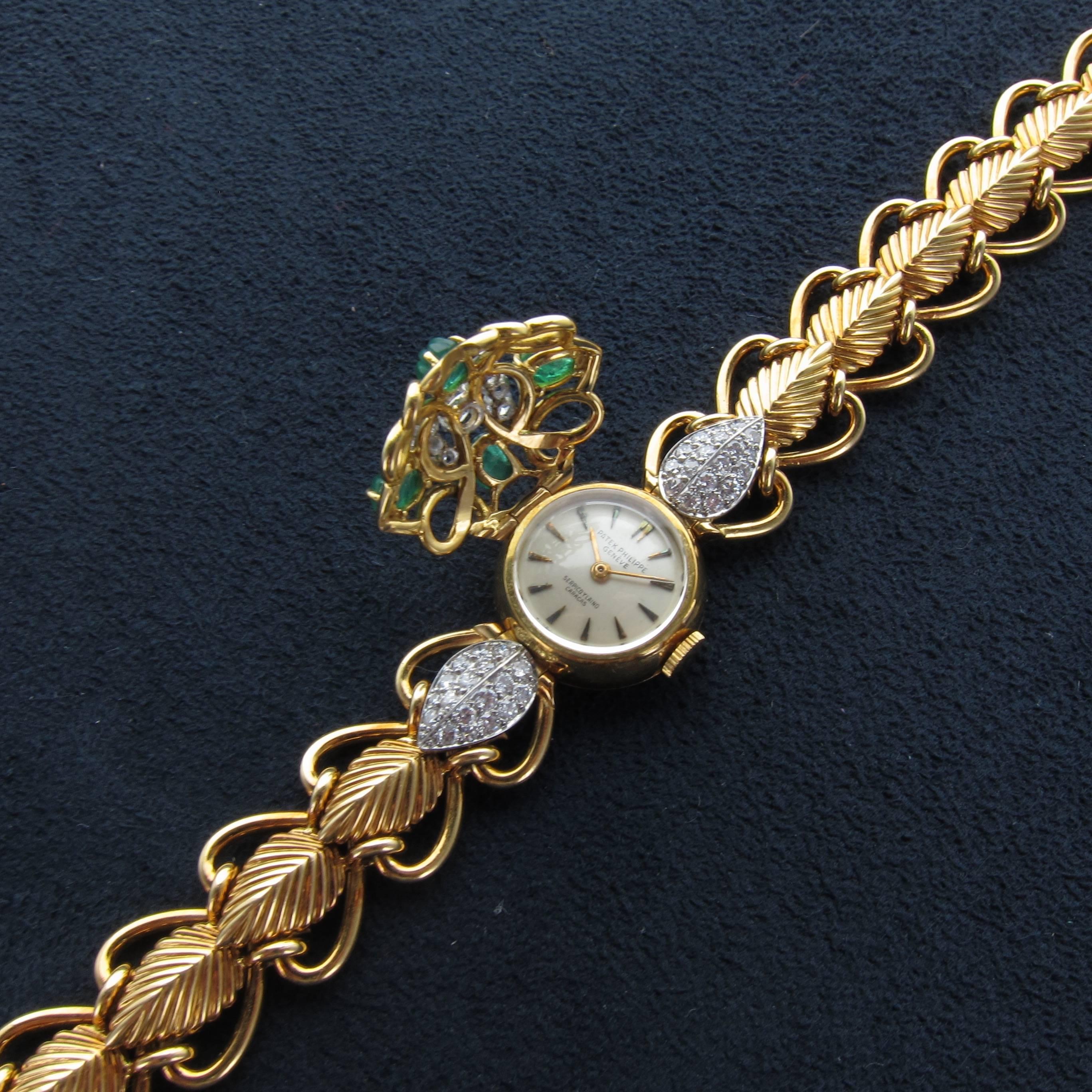 A 1950's Lady's Patek Philippe Diamond & Emerald Concealed Dial Bracelet Watch Retailed by Serpico Y Laino of Venezuela. Integral carved Emerald Leaf design with heart link bracelet. Dial marked 