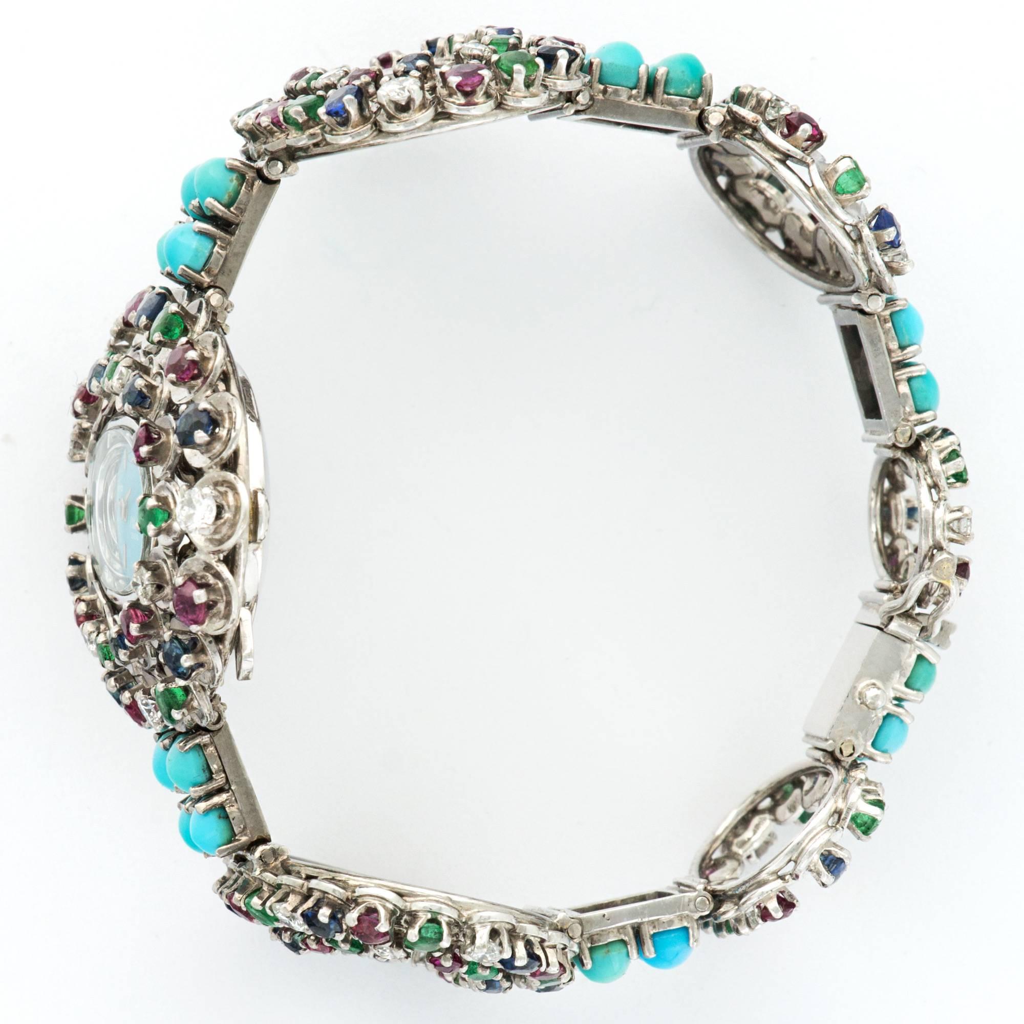 A Truly Unique 18k White Gold Wide-Link Bracelet Watch with Diamonds, Rubies, Sapphires, Emeralds and Turquoise. 

Manual Wind Movement

Circa 1970's