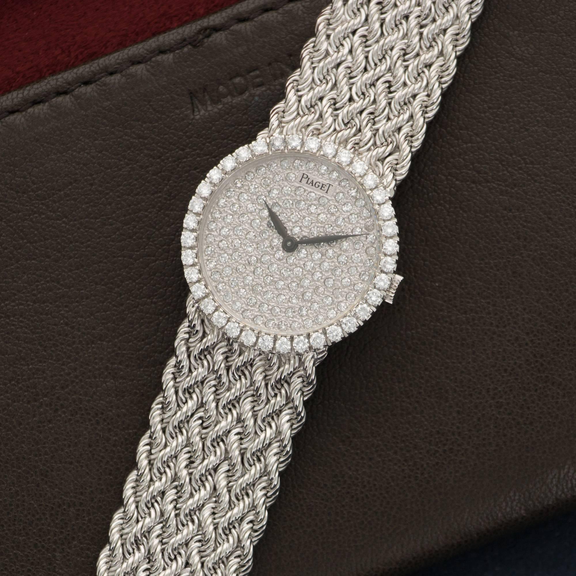 An 18k White Gold Wove-Link Bracelet Watch by Piaget. Full Original Pave Diamond Bezel and Dial. Mechanical Wind. 26mm Diameter Case. Circa 1970's