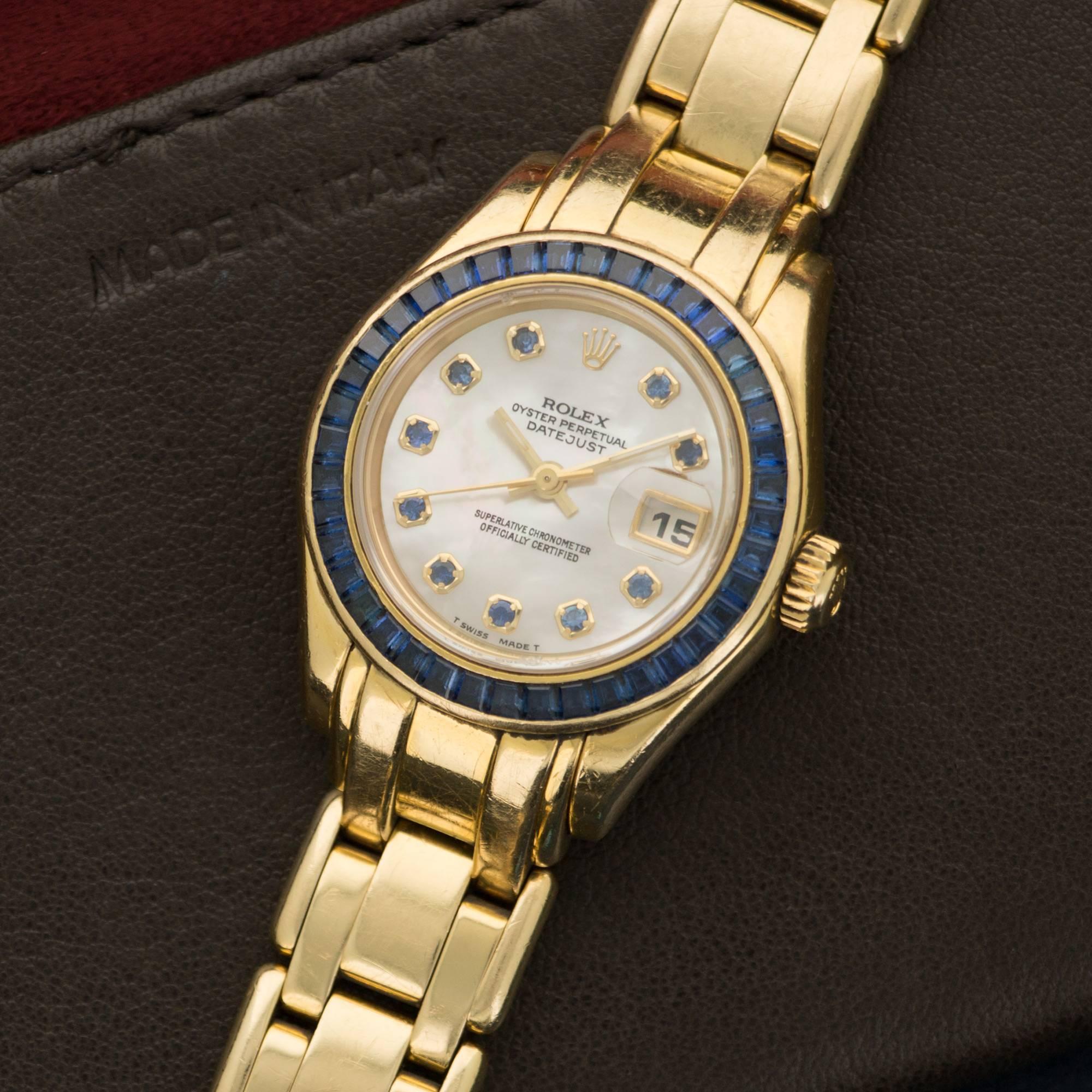 An Beautiful 18k Yellow Gold Rolex "Pearlmaster" Model with Original Square-Cut Sapphire Bezel and Mother of Pearl Dial. All Original. Model Number 69308. Circa Early 1990's .