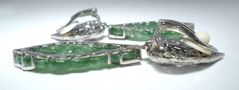 One Pair of Earclips,
with two green jade engraved plates in diamond shape, 
34.5 x 22 mm, 5.4 g,
and 100 Diamonds and 6 Diamonds, baguette cut,
together 1.00 ct.,
mounted in Platinum and 750/- White Gold

Total Weight 28.7 gr.

    100