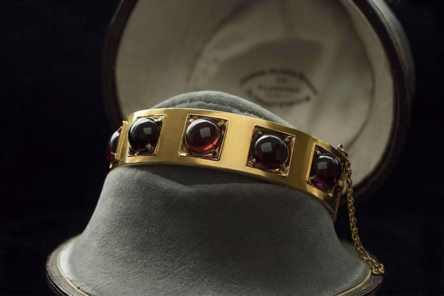 Victorian gold bangle with 5 circular-cut garnet cabochons. The bangle is 14k yellow gold. Each cabochon somewhat varies in its hue. This piece is great for stacking, or looks great on its own. The hinge is secure, and shuts firmly. (safety chain