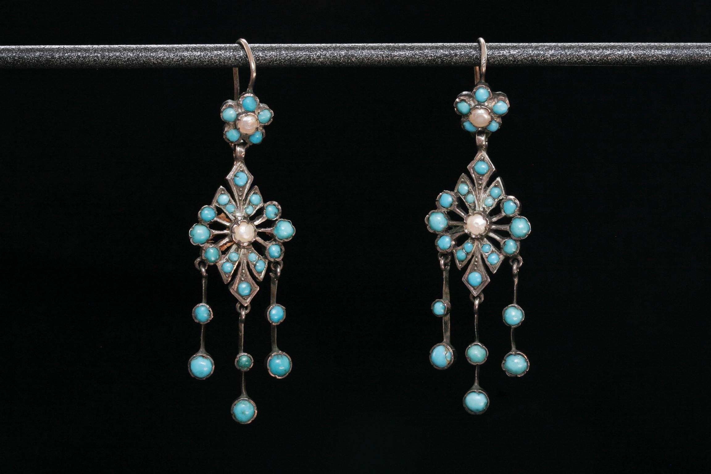 C.1860. A very pretty and delicate turquoise chandelier earrings.
A diamond shaped centerpiece is adorned with small turquoise stones with a seed pearl at the center. Additionally, three delicate strands with two turquoise stones hang from the