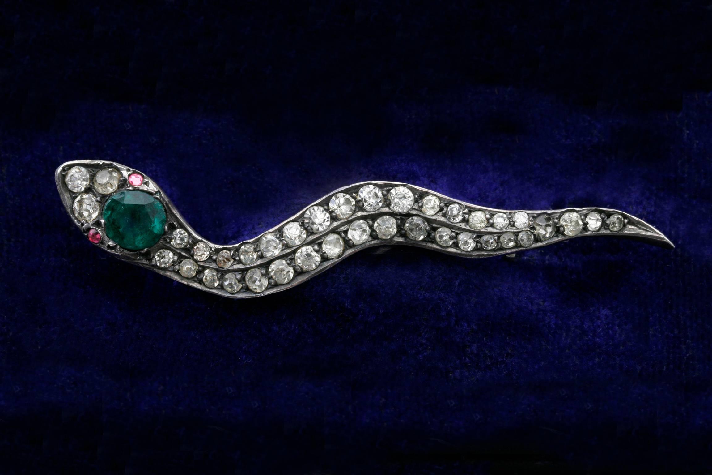 C.1910.  A lovely snake brooch set in sterling silver, stamped 935 (a common sterling stamp in Germany, Austria and Switzerland). Created throughout with glittering clear paste stones for the snake’s body, the brooch features emerald and ruby