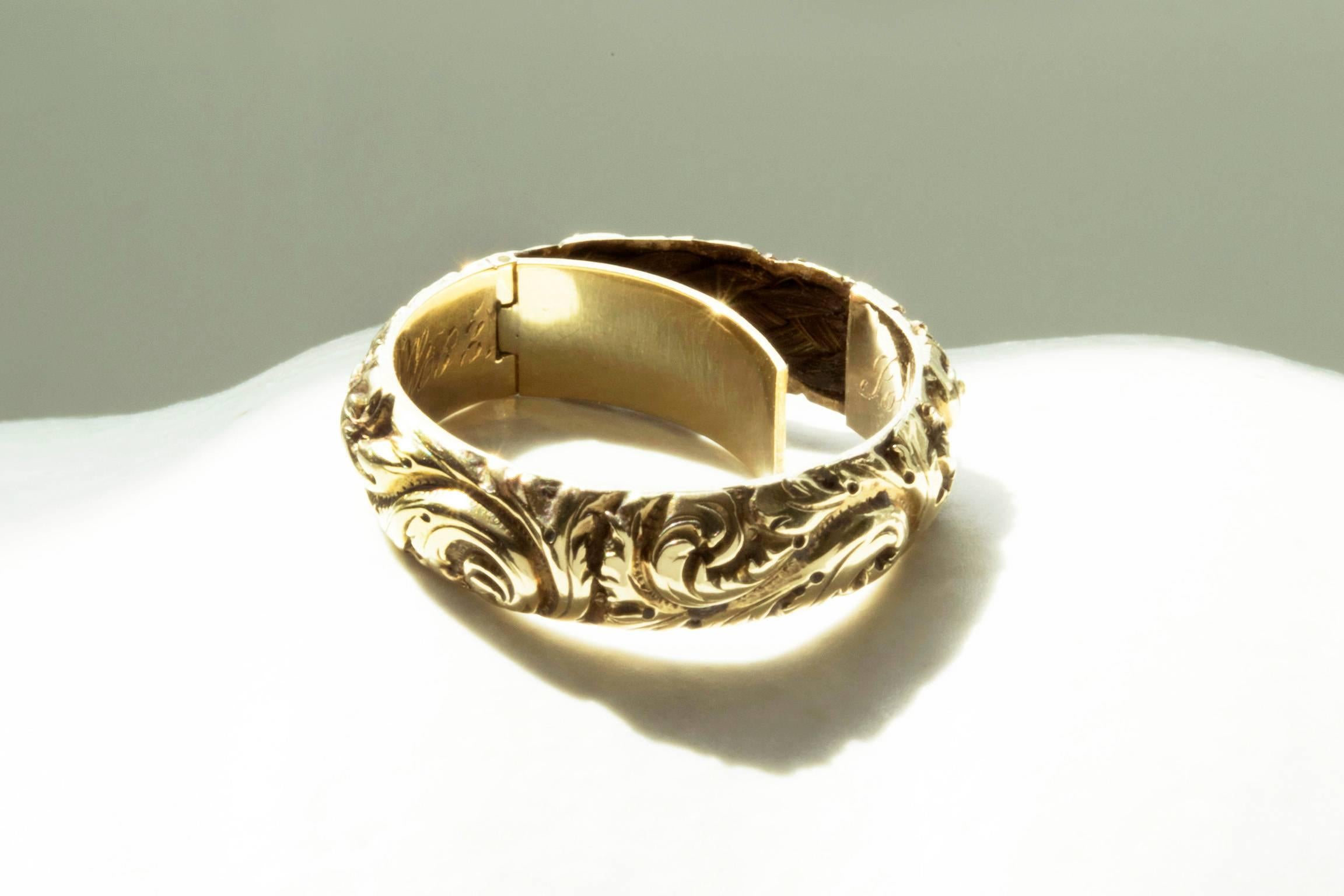 C.1822. A beautifully chased Georgian gold band with a hidden compartment. The band has a secret compartment that opens from inside. It contains a lock of woven hair that has remained intact. The inscription at inner band reads- John Hardwick, ob,