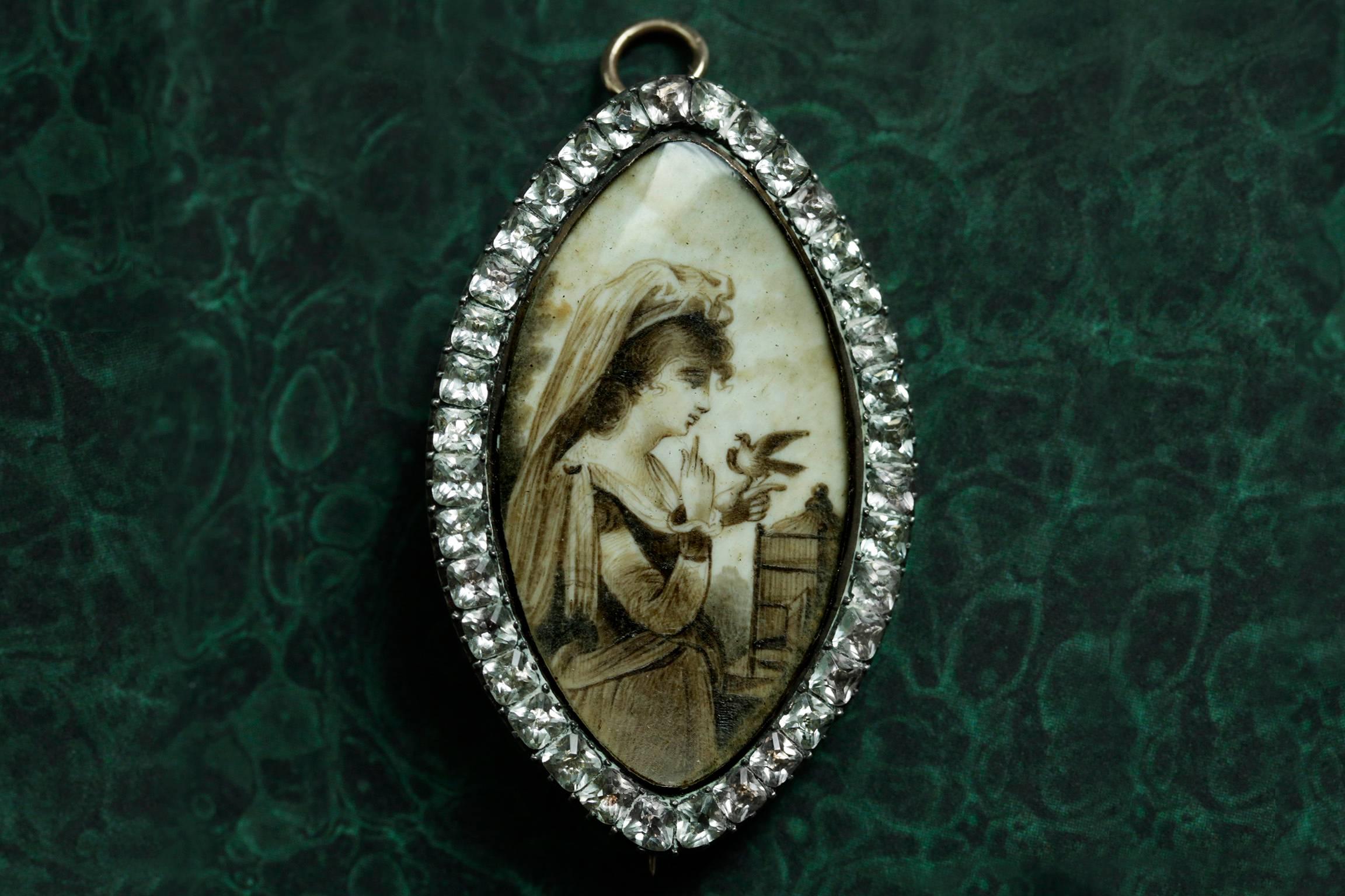 C.1780-1800. A gorgeous late 18th century sepia miniature pin/pendant. The finely executed sizable navette-shaped miniature painting depicts a young lady gently holding a dove released from its cage. A dove symbolizes peace or holy spirit. The pin
