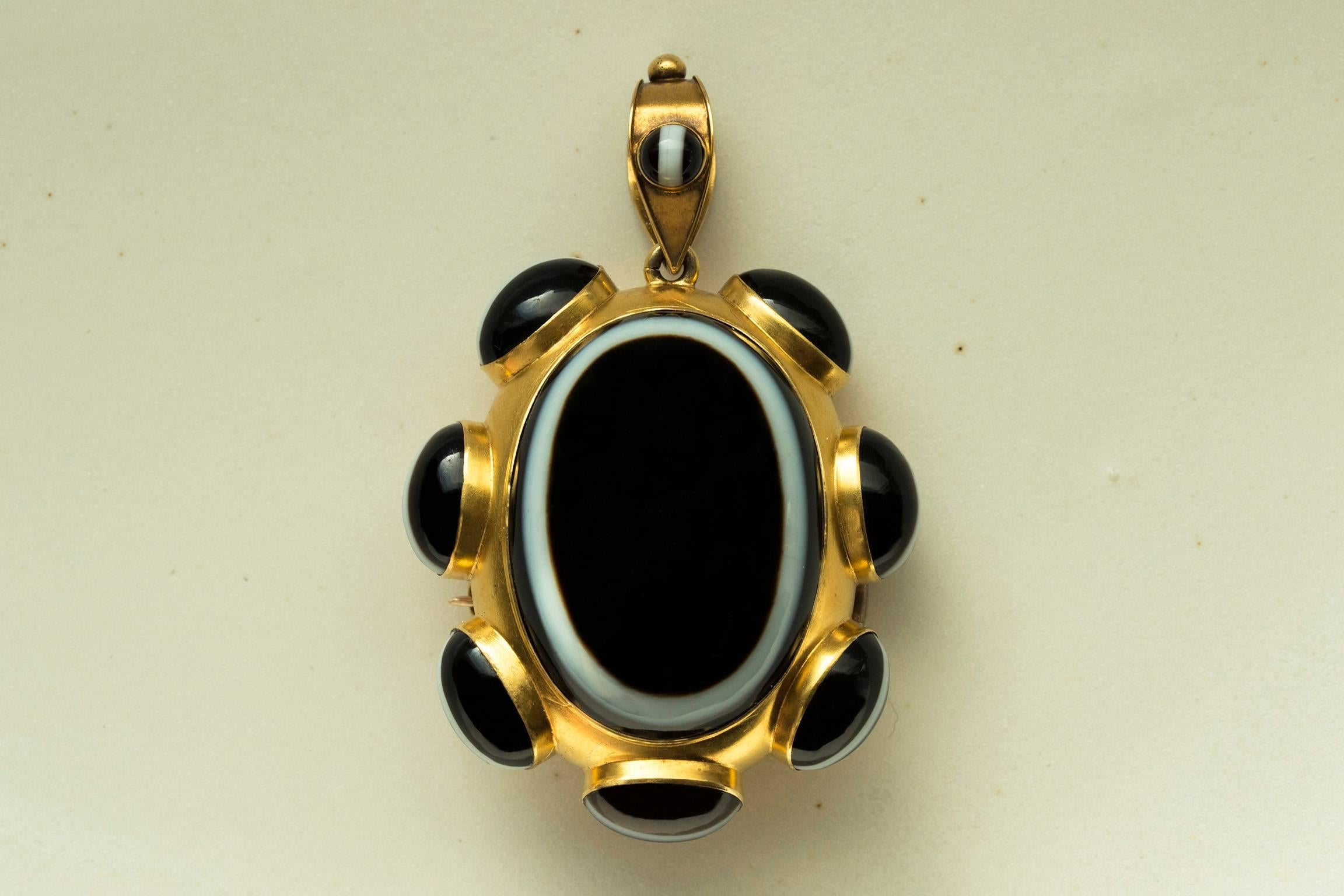C.1870. A high quality Victorian banded agate gold oval pendant/pin with a locket compartment on the back. With the rich contrast of black and white, the consistent banding patterns and colors correspond beautifully. A small matching banded agate
