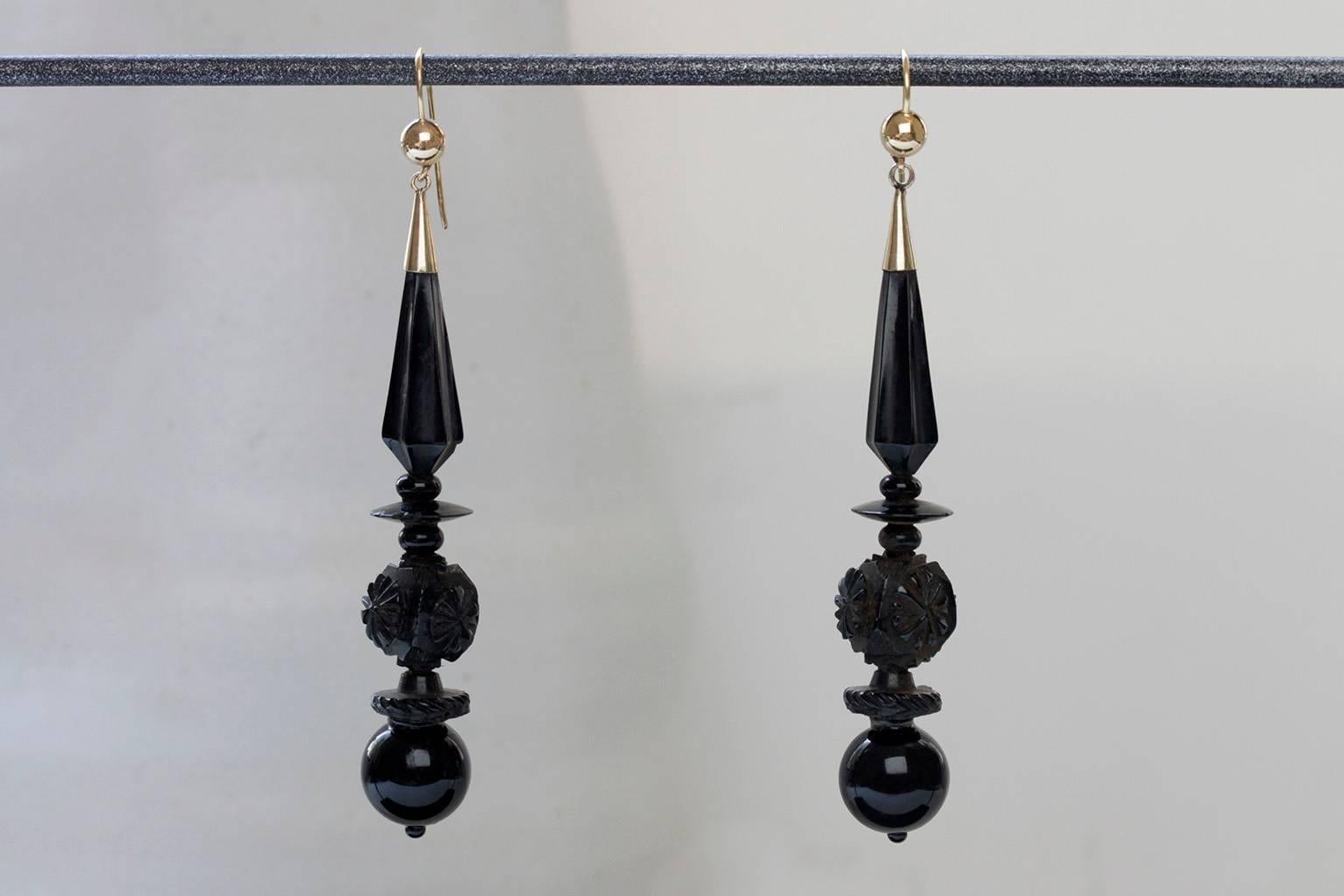 C.1880. A gorgeous pair of Victorian elongated carved Whitby jet drop earrings. The earring is lightweight, and now have new 14k gold ear wires. A few flea bites are shown when inspected closely around the second tier (round plate) in one earring.