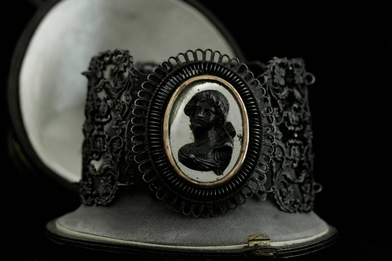 C.1820-1830. This wide Berlin iron bracelet consists of six individual rectangular cast iron plaques with a scrolled foliage motif. The central raised section of the beautiful female cameo /psyche on its golden-framed polished steel oval is attached