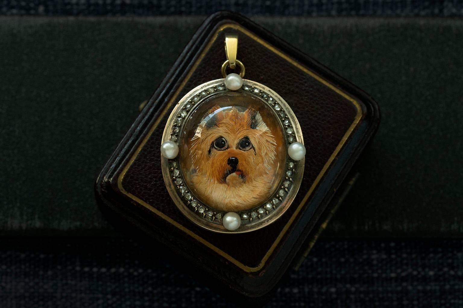 An adorable Victorian Essex crystal reverse intaglio locket. This 18k gold locket features a Norwich terrier surrounded by rose cut diamond row and extra pearls at four additional points. The technique of reverse intaglio crystal carving required