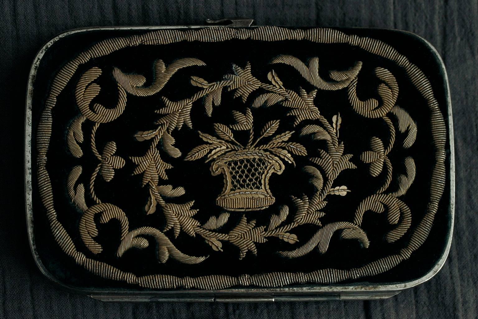 C.1870. A beautiful Victorian purse with hand-embroidered work. The dark green velvet is decorated with golden threads and beads. The purse has a metal frame with a snap closure placed at the top center. Inside, it contains a small notebook and a