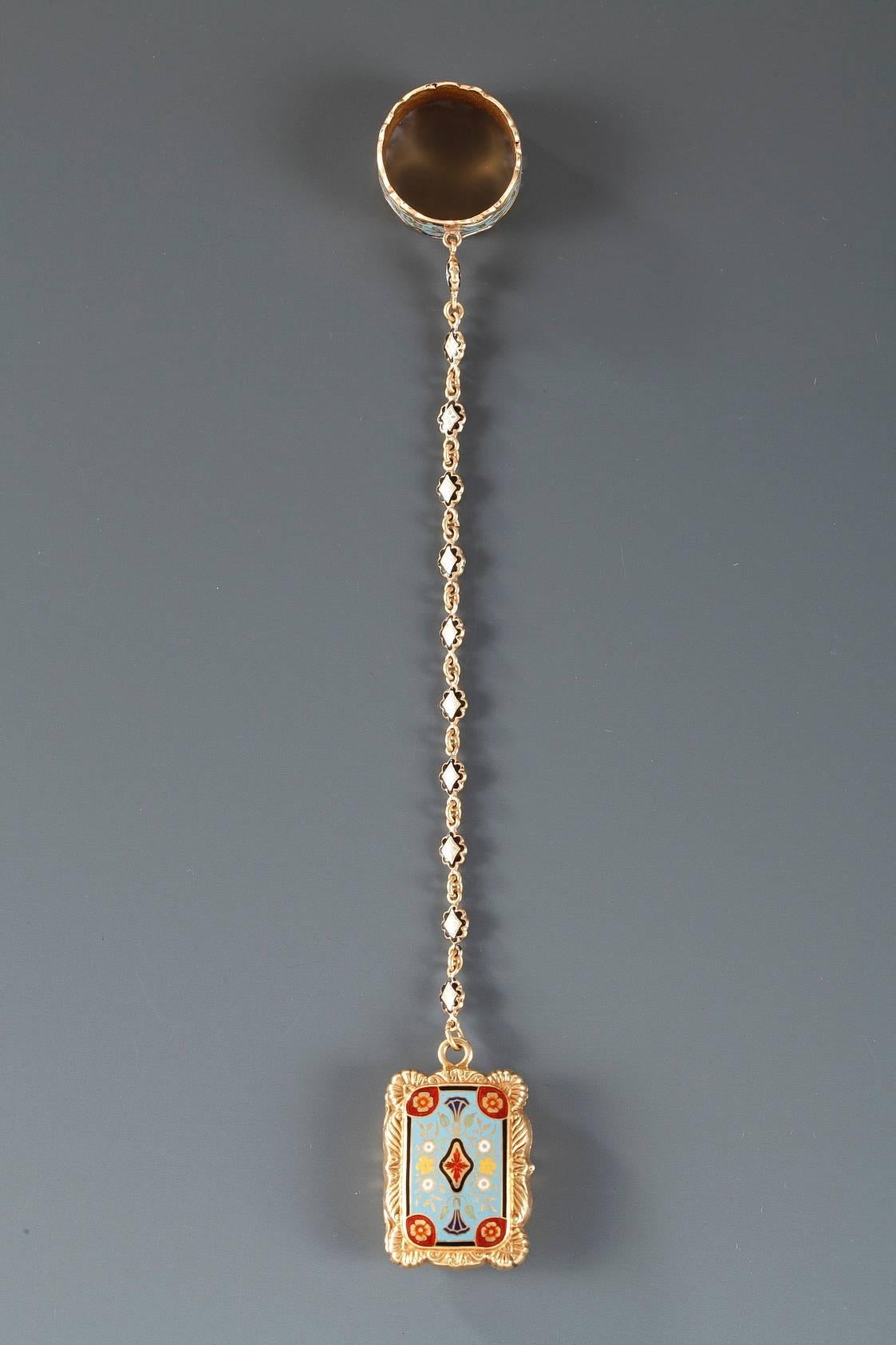 Nineteenth century vinaigrette in 18 karat gold, enameled on both sides with a brightly colored floral composition. A delicate chain connects the vinaigrette to an elegantly enameled ring, highlighted with scroll work and golden floral motifs. The