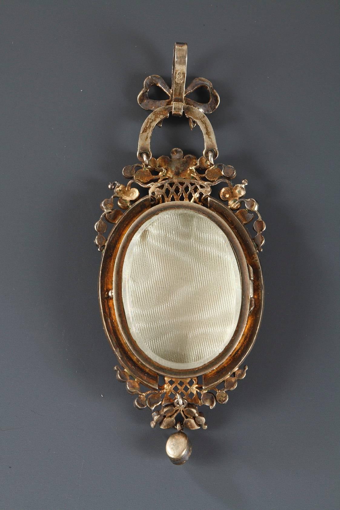 Silver-gilt pendant featuring a mythological scene on enamel representing La Fontaine de l’Amour (The Fountain of Love) after Jean-Honoré Fragonard. The setting is meticulously executed, embellished with delicate pearls, rubies, and emeralds that