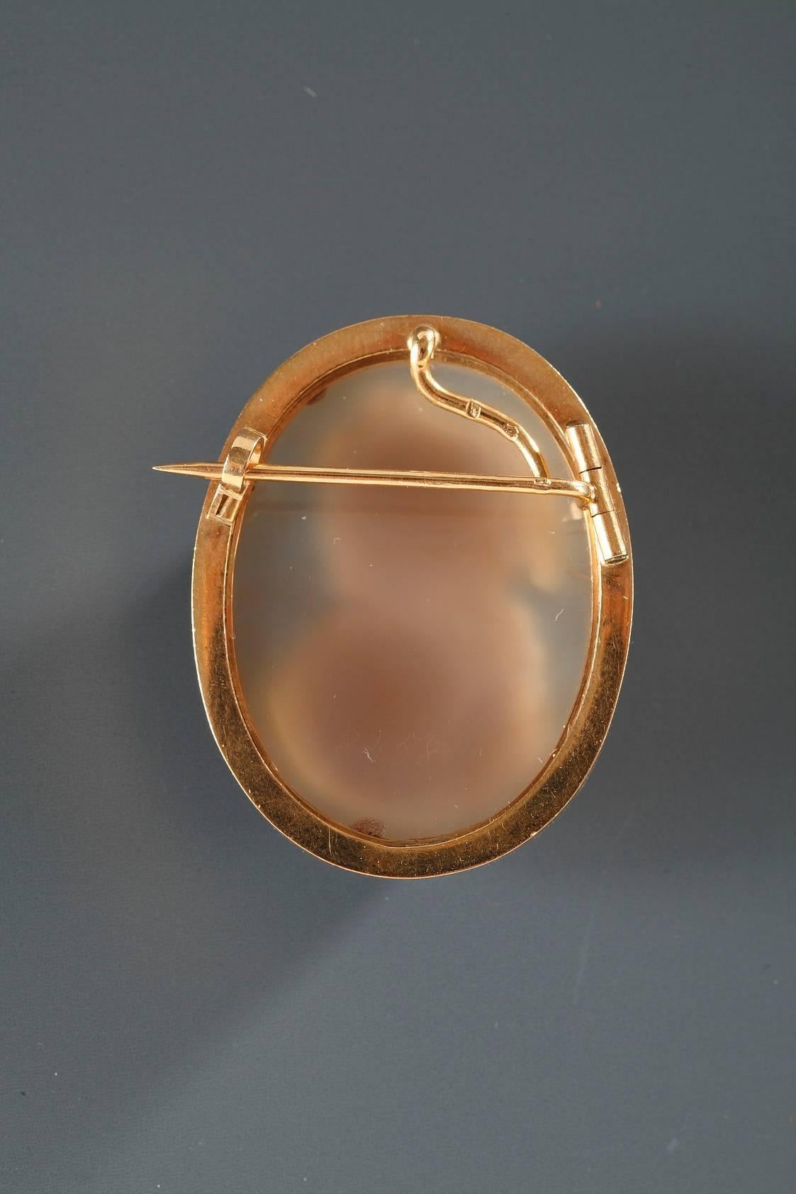 Gold brooch with a shell cameo featuring the bust of a young woman wearing ribbons in her hair. The necklace and earrings she is wearing have a star motif on them. 19th century work.
 
Circa : 1850

Dim: L: 1 in, W: 0.4 in, H: 1.6 in
Dim: L: 3