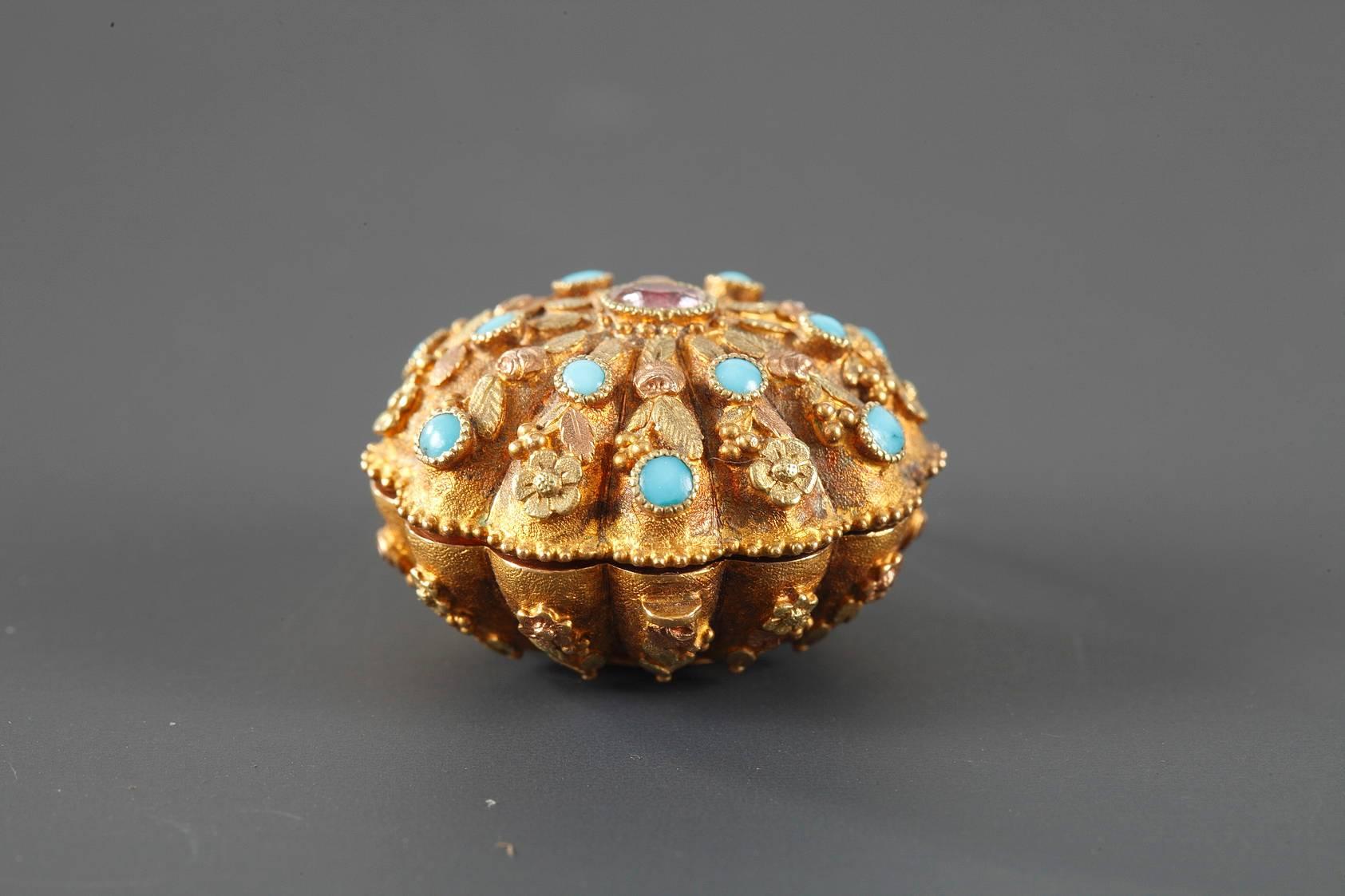 Shell-shaped vinaigrette pendant intricately sculpted with flowers and seeds in two shades of gold. The lid is decorated with a ruby cabochon surrounded by small turquoise beads. The interior grill is in the shape of leaves and serves to hold in