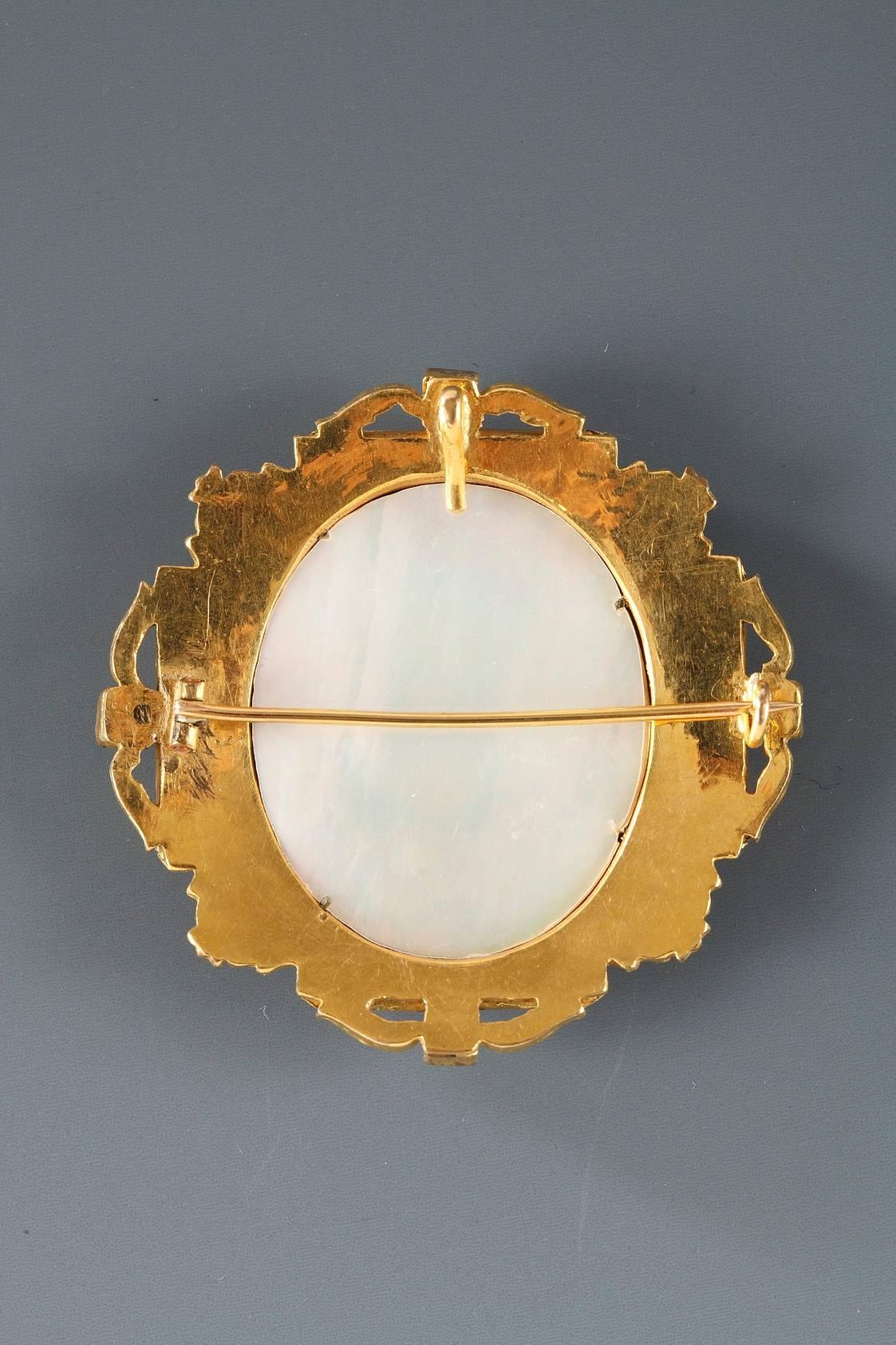 Exquisite brooch with a mother-of-pearl medallion featuring the bust in miniature of a young girl wearing pearls, on a gray background. The gilt-brass mounts are highlighted with emeralds, sapphires, and ruby cabochons. Napoleon III period.
