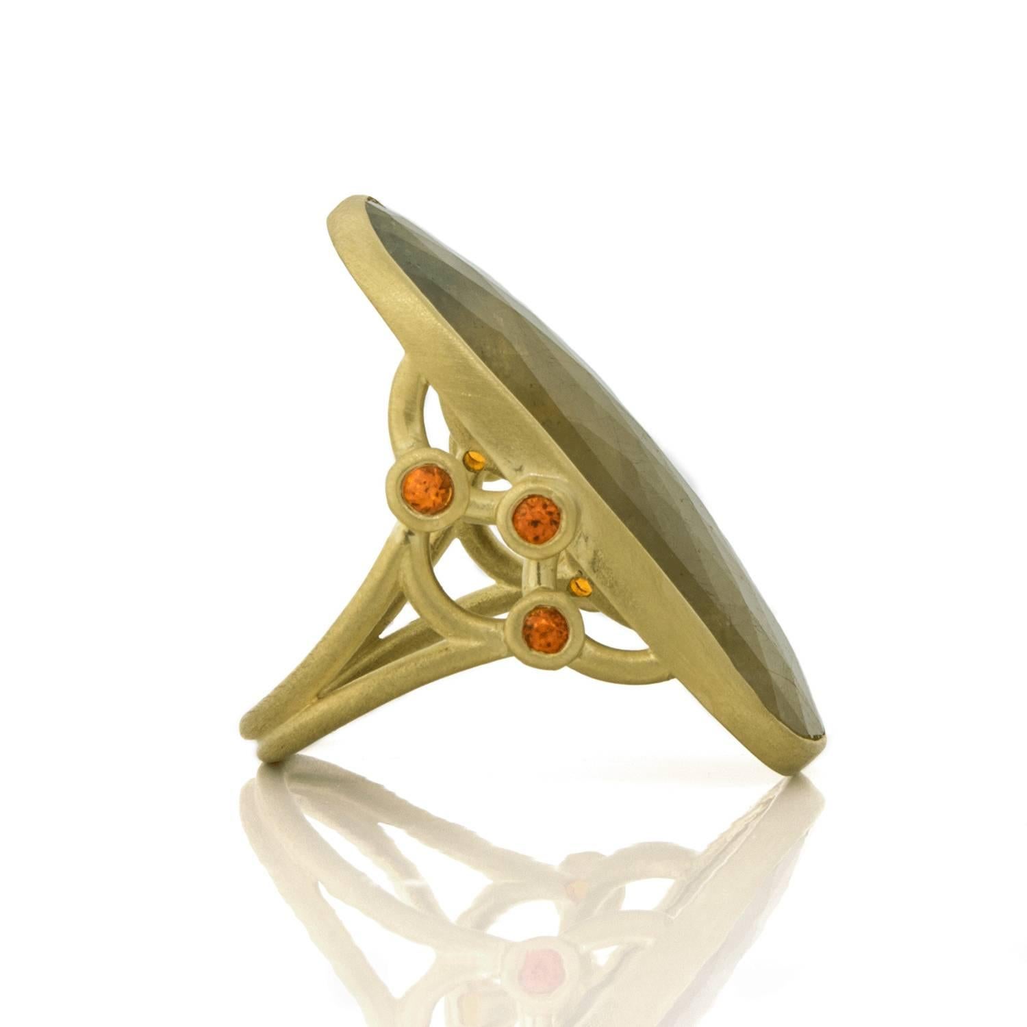 A great statement piece!  Long and elegant, the green sapphire center stone is rose cut, slightly curved for comfort and set in an 18k green gold bezel.  Embellished with triple granulation beads set with bright orange mandarin garnets. 