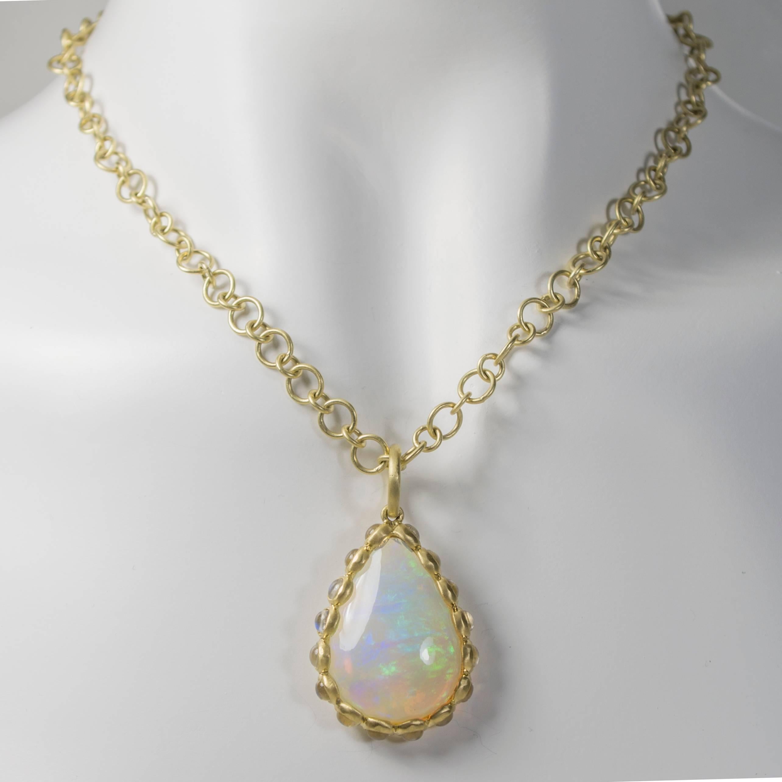 Be prepared for swooning glances with this incredible, one-of-a-kind Ethiopian opal and moonstone pendant.  The handmade setting is 18k green* gold featuring a 9.13 cts. pear-shaped opal surrounded by 16 bezel set moonstones.  Incredible color in a
