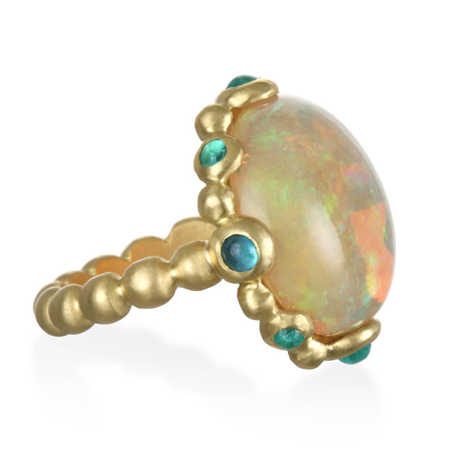 Faye Kim's 18k gold* Ethiopian Opal ring is handcrafted in 18k gold.  
Vivid blue-green Paraiba Tourmaline cabochons enhance the play-of-color displayed in this 9.02 carat opal.  Diameter is 5/8