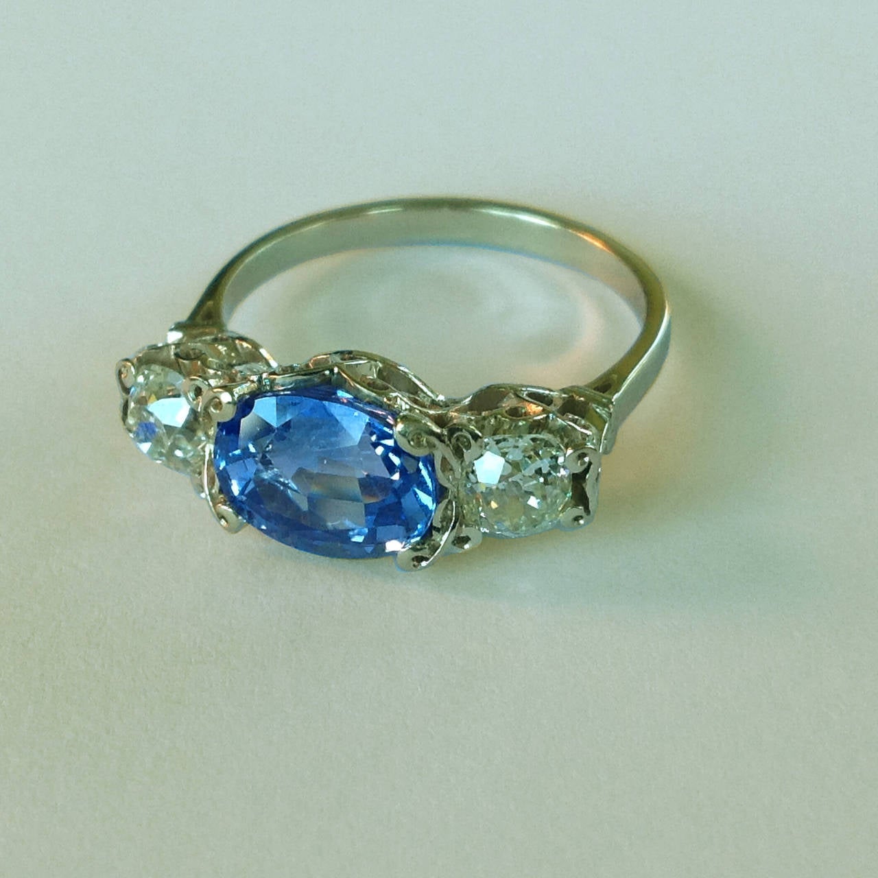  Bague de fiançailles en or blanc 19 k Dalben avec un saphir bleu clair de taille ovale de 2,77 carats et deux diamants de taille ancienne d'un poids total de 0,81 carats.

Taille de bague 7 1/4 - EU 55 adaptable à la plupart des tailles de doigt.