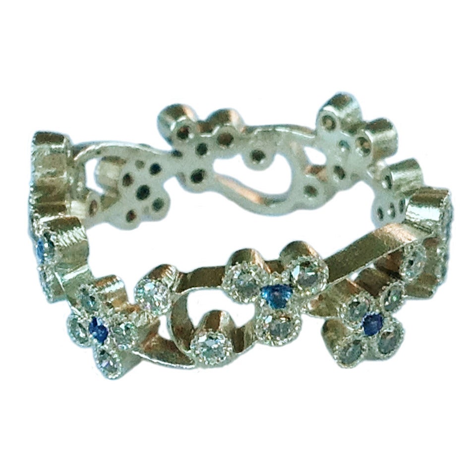 Bague bandeau floral en diamants brun clair et saphir bleu clair montée en or blanc gravé 19 carats avec 40 diamants bruns ronds de taille brillant pesant au total 0,53 carats et 10 saphirs bleus clairs de taille ronde pesant 0,15 carats .
Bague