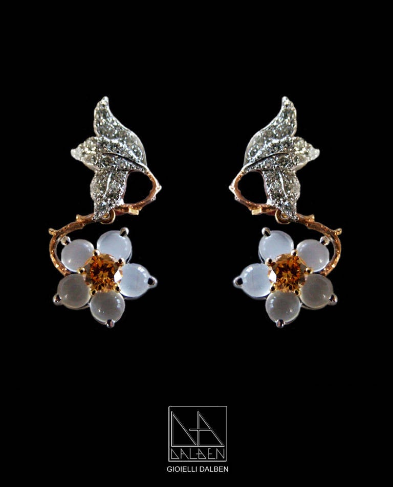 Dalben design earrings inspired by the flower hellebore with 2 fancy orange round brillant cut diamonds weight tot. 0,71 carats in the center surrounded by 10 moonstones and 0,48 carats white round brillant cut diamonds mounted in 18 kt white and