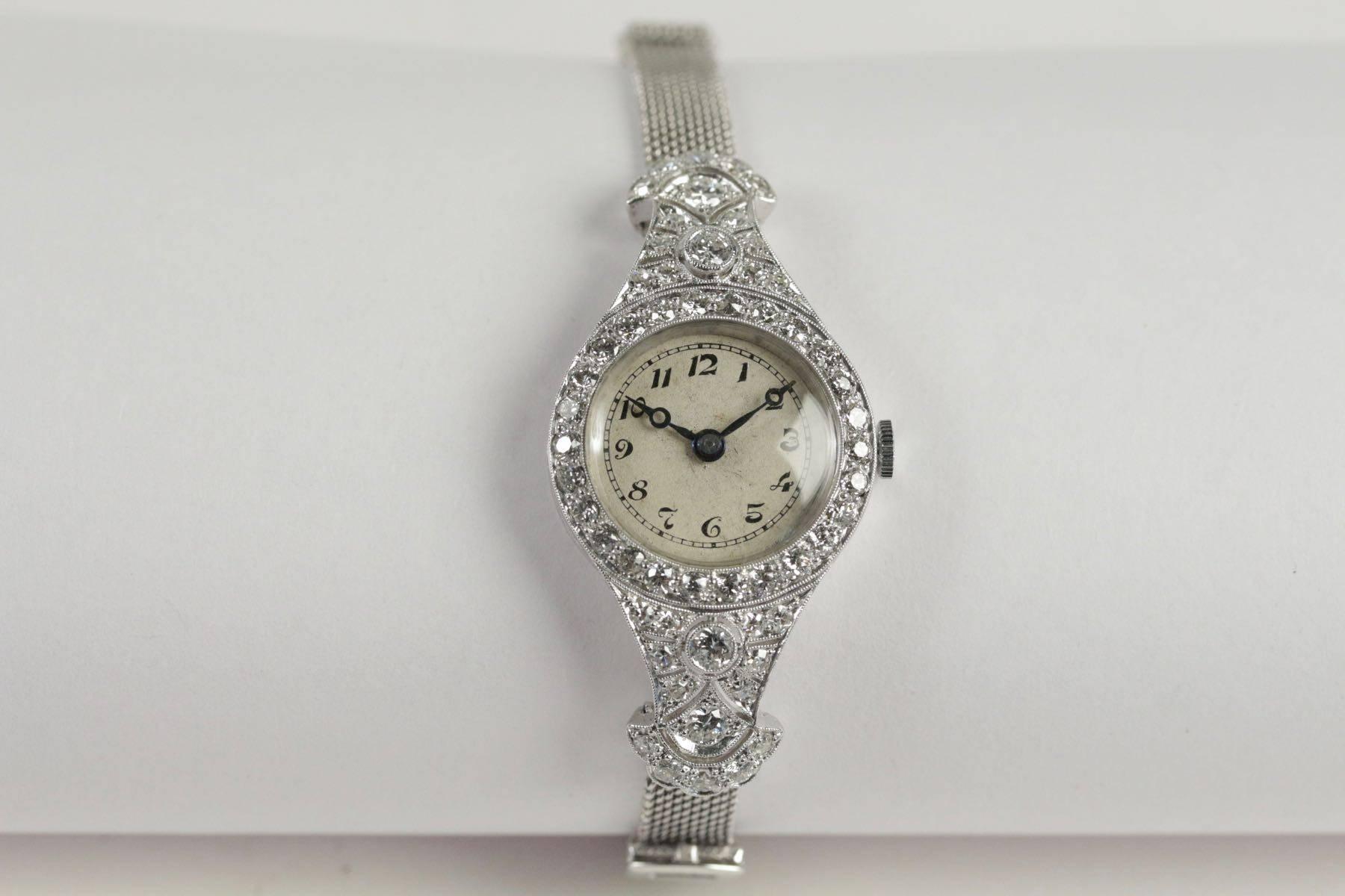 Art Deco ladies watch mounted in platinum, set with brillant cut diamonds (approximately 3.50 ct). Ivory colored dial with black Arabic numerals. 18k White gold rope bracelet. Manual winding.