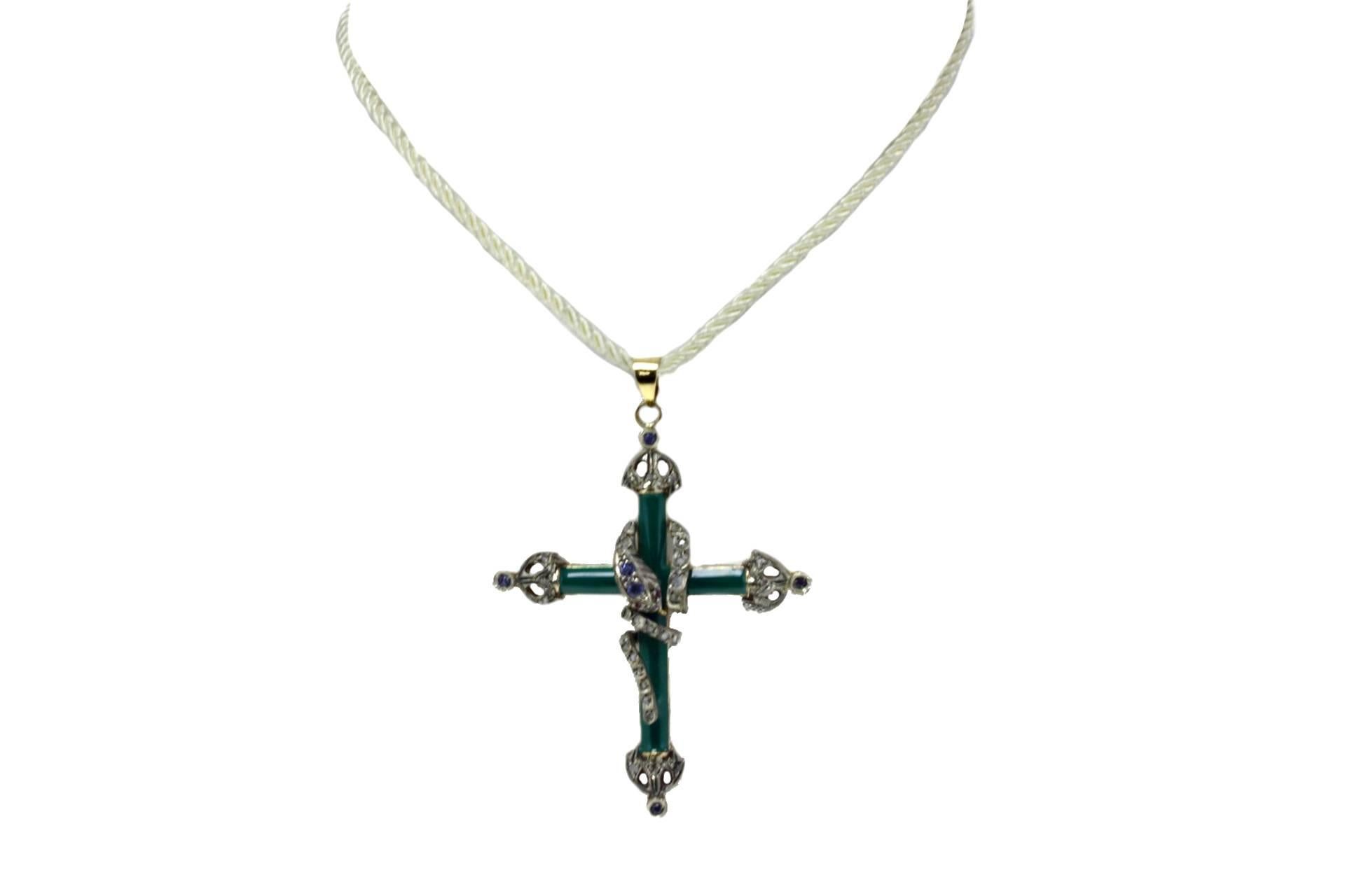 Green enamelled cross pendant in 14 kt yellow gold and silver, embellished with diamonds and sapphires and in the middle a twisted snake covered in diamonds, blue sapphires and rubies.

tot weight 10.2gr
r.f.  gafi