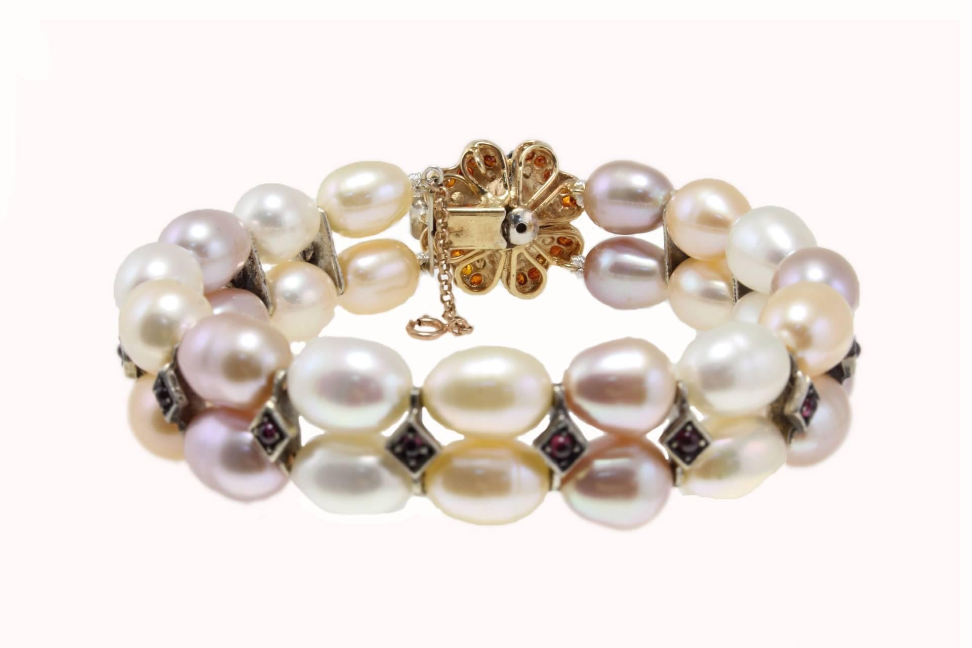 Classic beaded bracelet embellished of a clasp of shiny zircons  and details in garnets. Settled on 9 Kt rose gold and silver.
Tot weight 42.7 g
Gemstone 0.68  ct
Pearls 31.3 g
Garnets 1.05 ct

Rf. efe